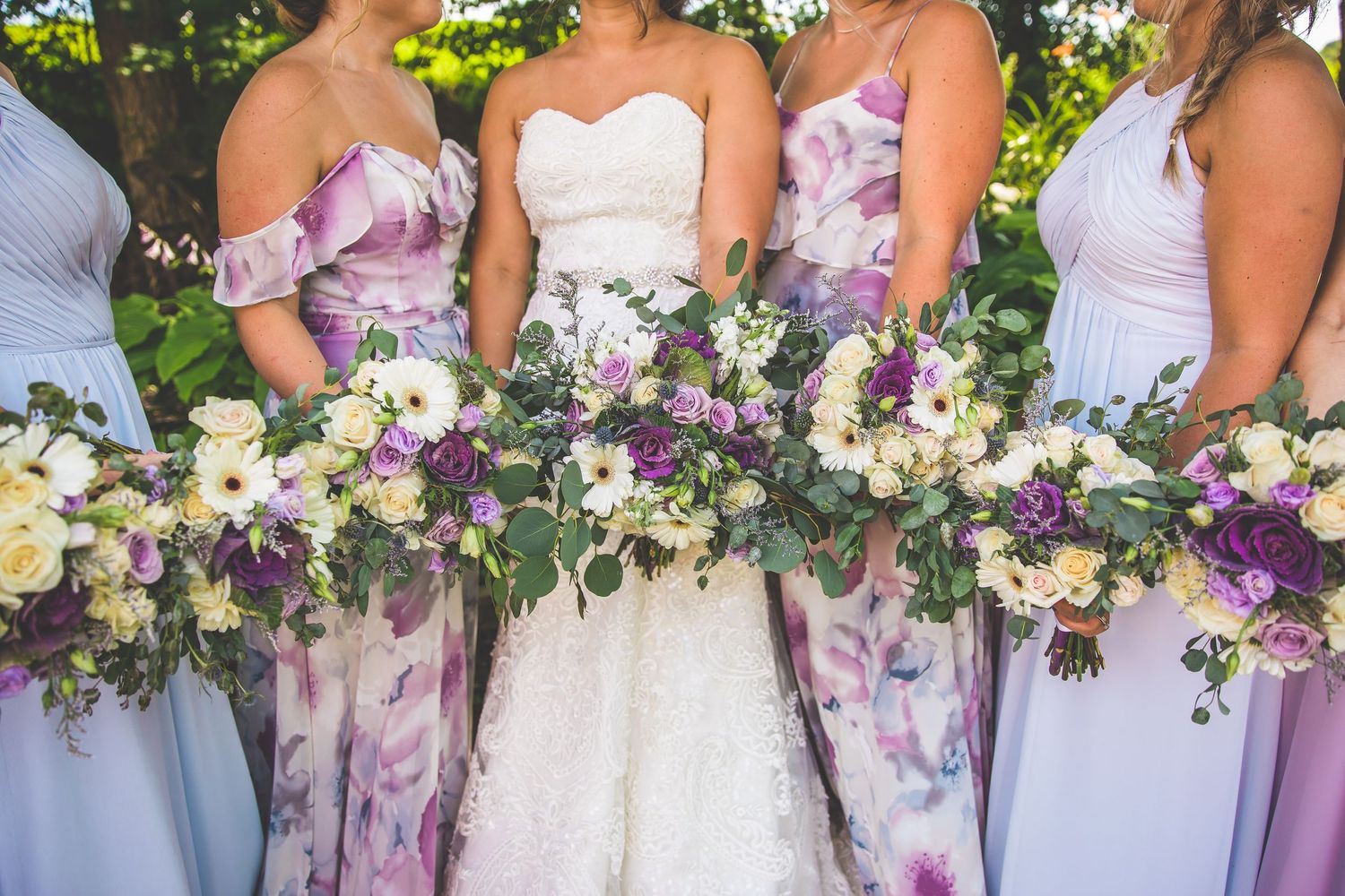 Detail shot of purple and white wedding bouquets held by bridesmaids in a row.