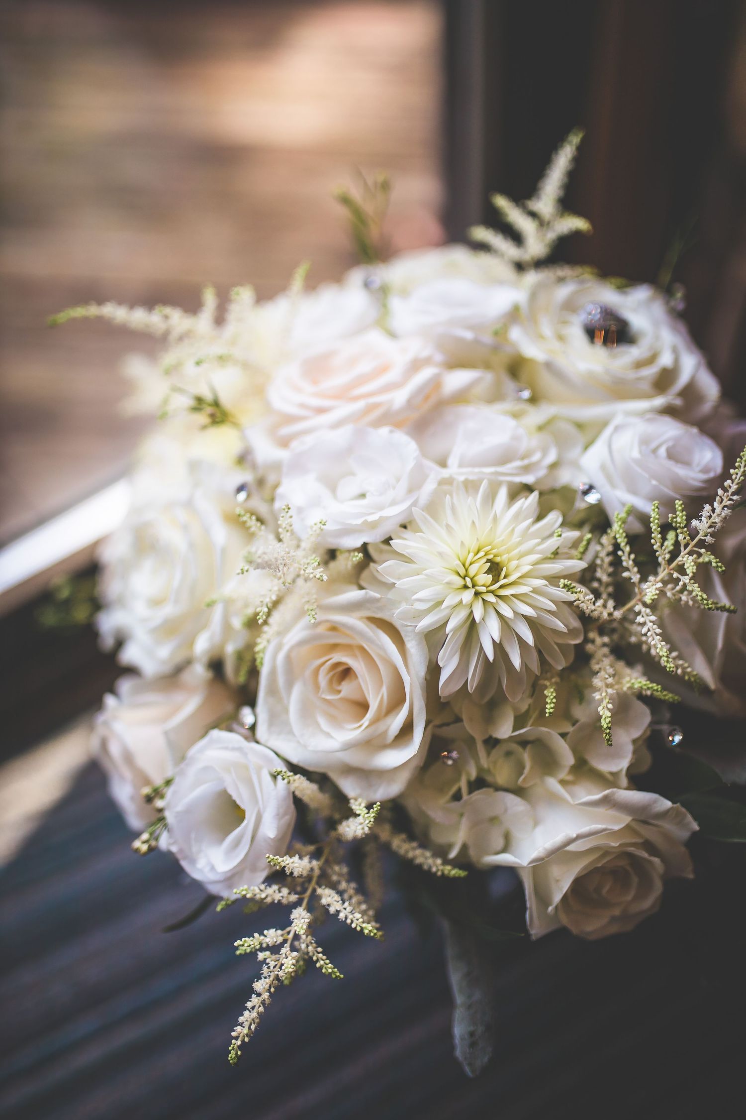 Elegant white rose and dahlia wedding bouquet with delicate greenery.