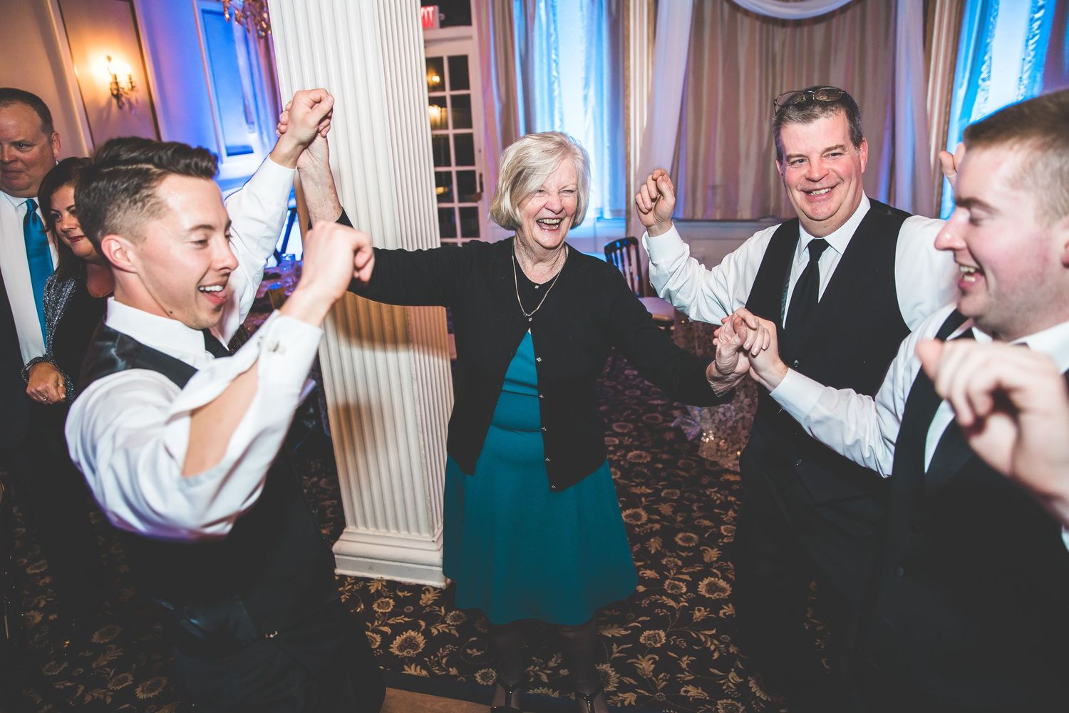 Wedding party enjoying lively dancing and celebrations in an elegant ballroom setting.