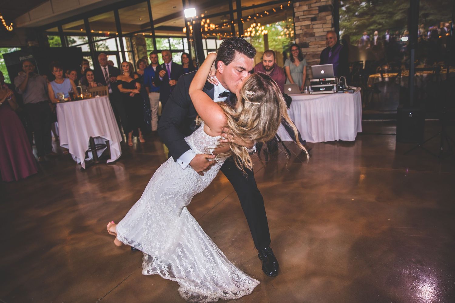 Couple performing a dramatic dance dip move during their wedding reception on a polished floor.