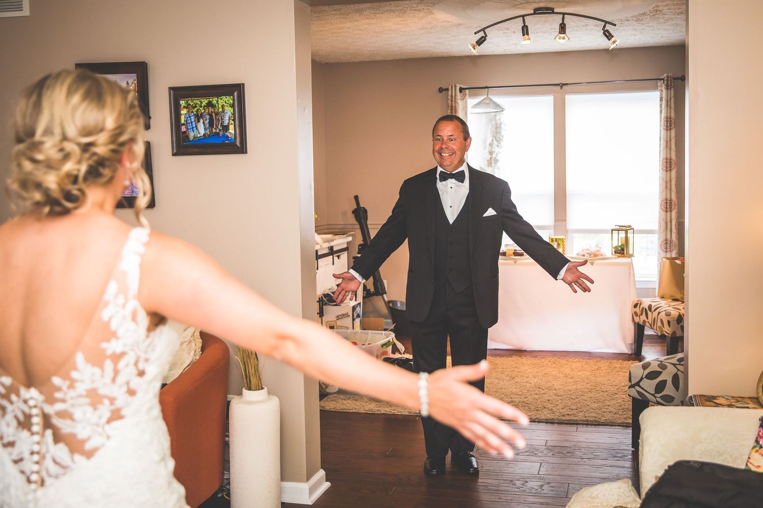 Wedding party members getting ready in a beige-toned room with track lighting.