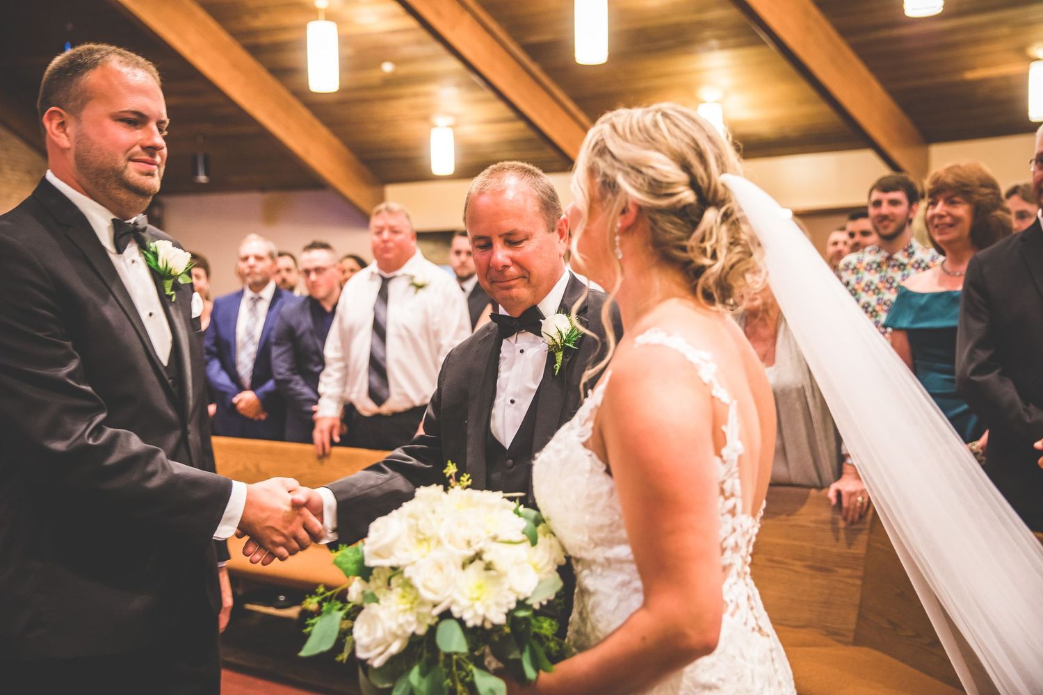 Wedding ceremony taking place in a rustic wooden-beamed venue with elegant lighting.