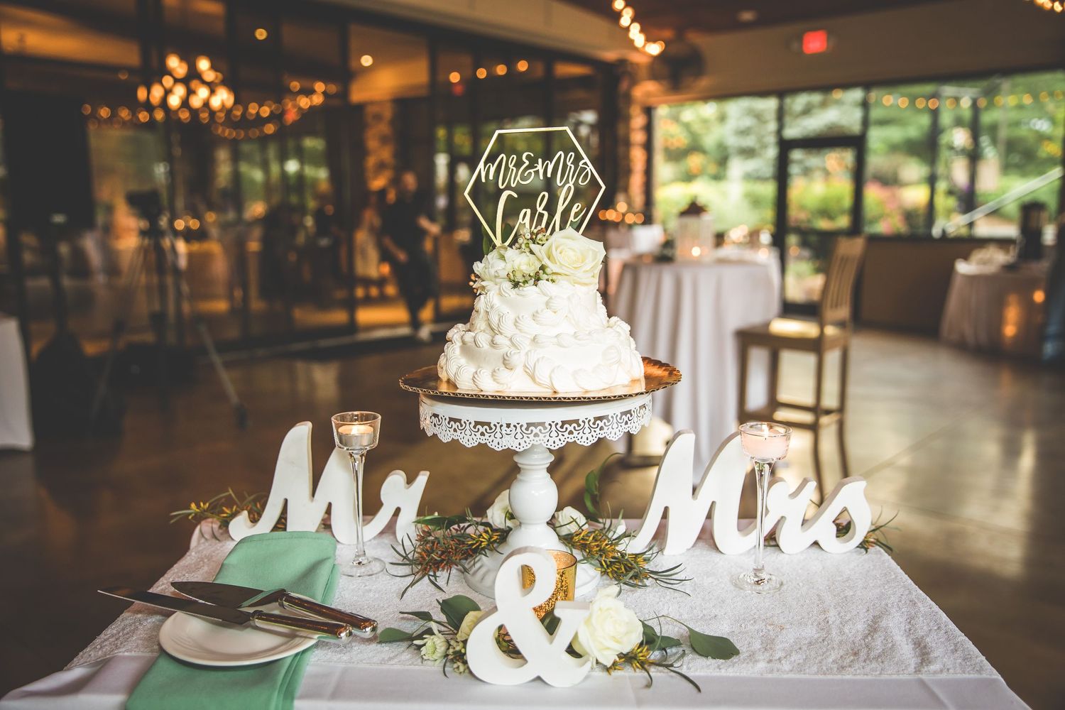An elegant white wedding cake displayed with Mr and Mrs signs on a decorative cake stand.