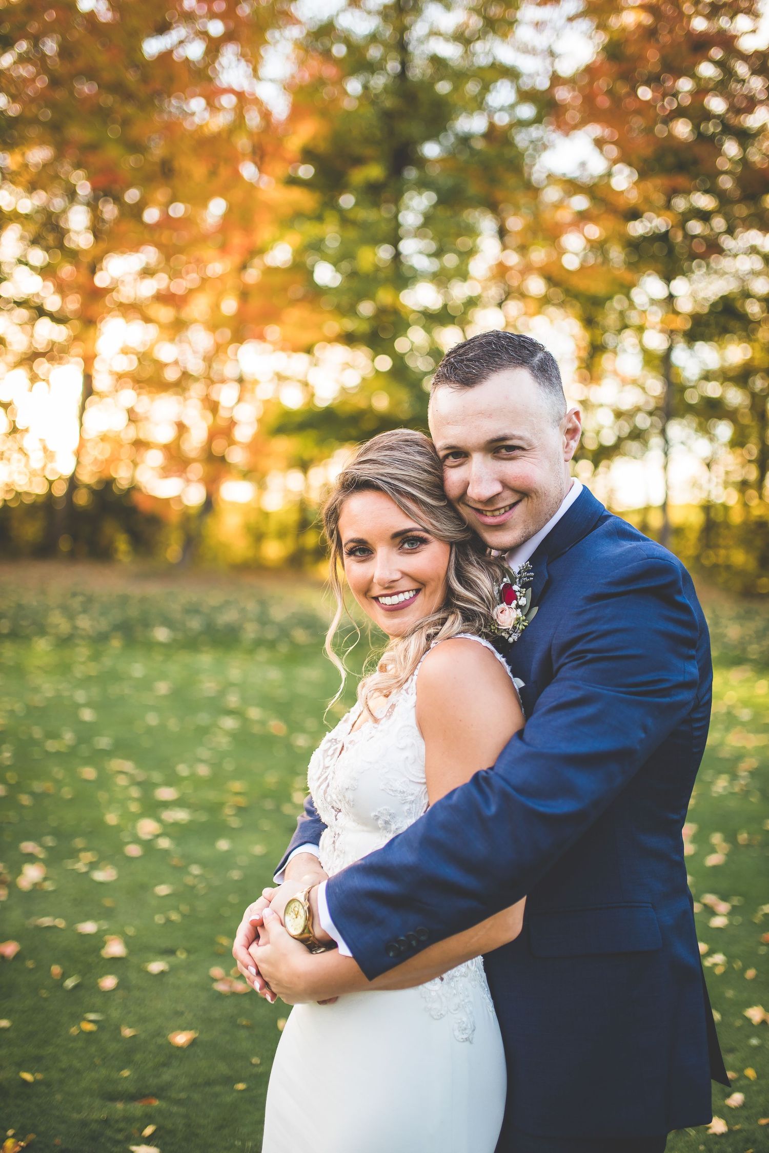 Romantic sunset portrait of newlyweds embracing in a golden-lit field.