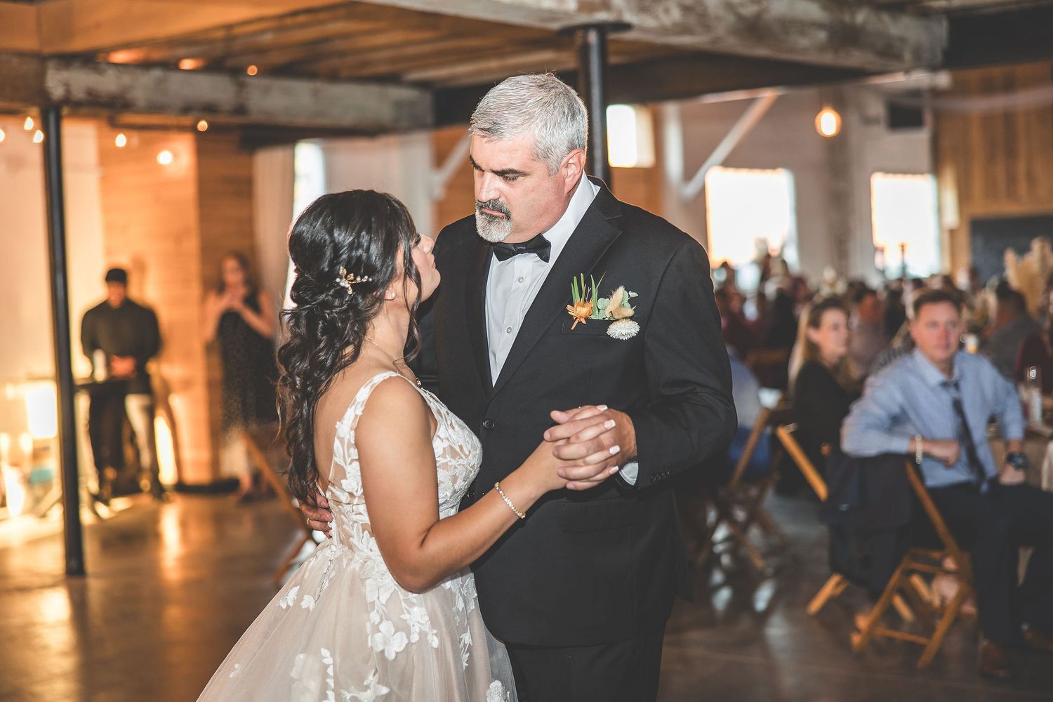 Couples share dances at rustic barn wedding reception under warm lighting.
