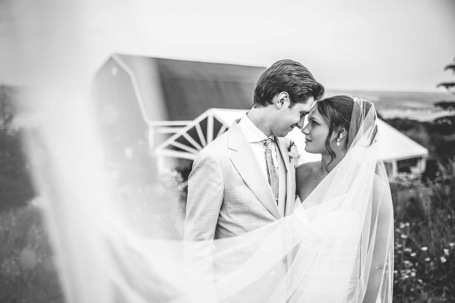 Romantic black and white wedding portraits captured against rustic farm backdrop.