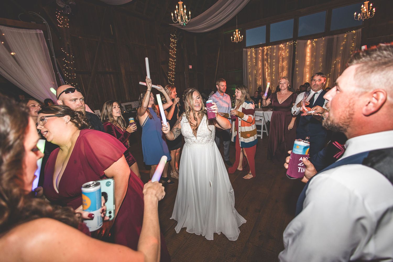 Energetic dance party at wedding reception with guests celebrating under ambient lighting.