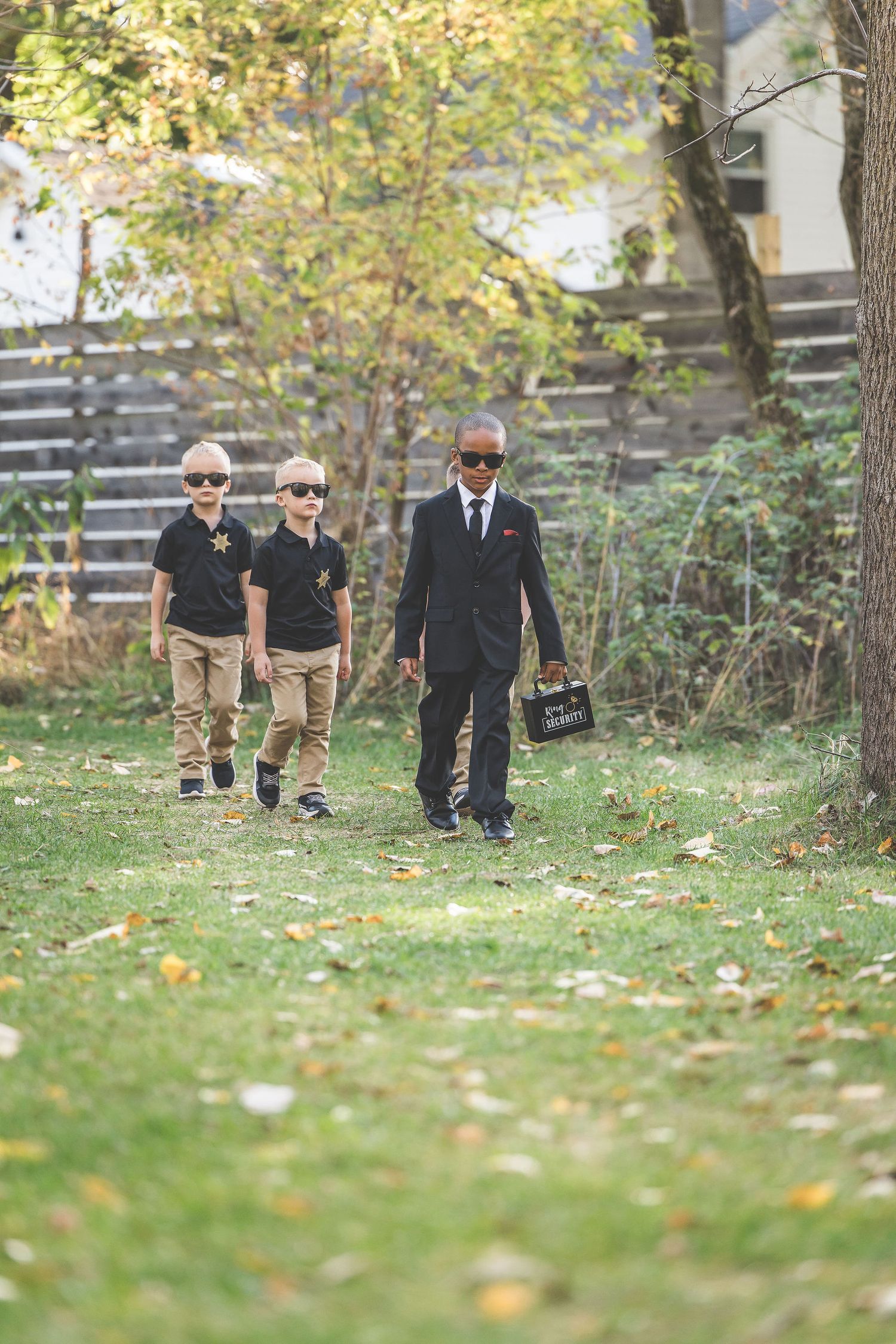 Three people walk down a garden path during an autumn outdoor event.