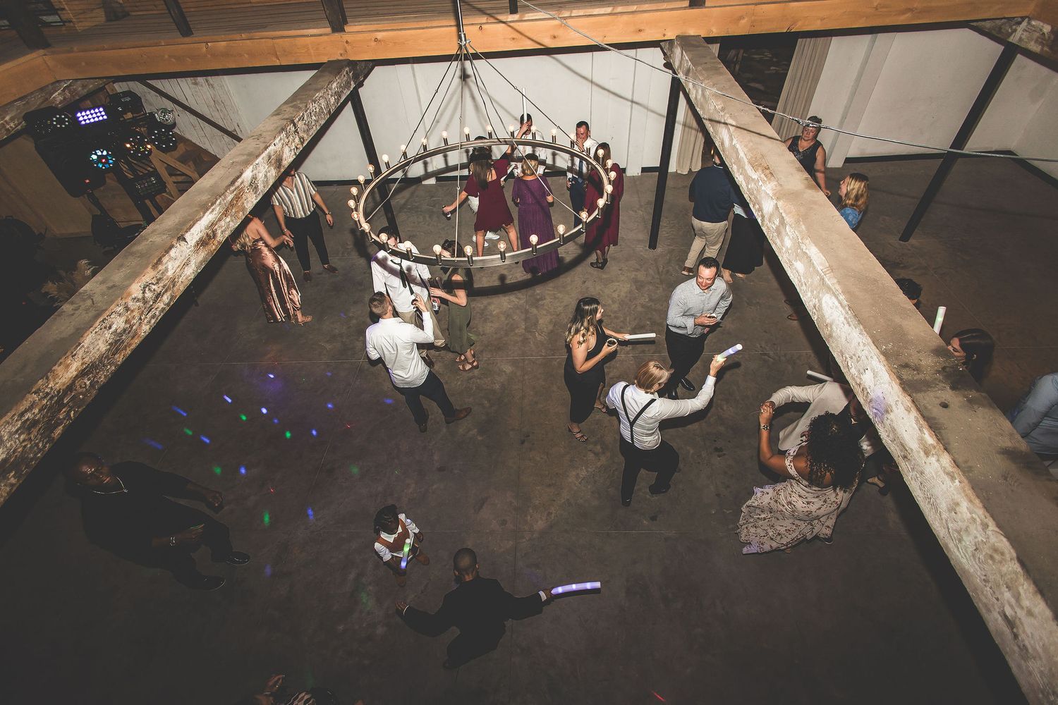 Aerial view of wedding reception dance floor in rustic barn with exposed beams and decorative lighting.