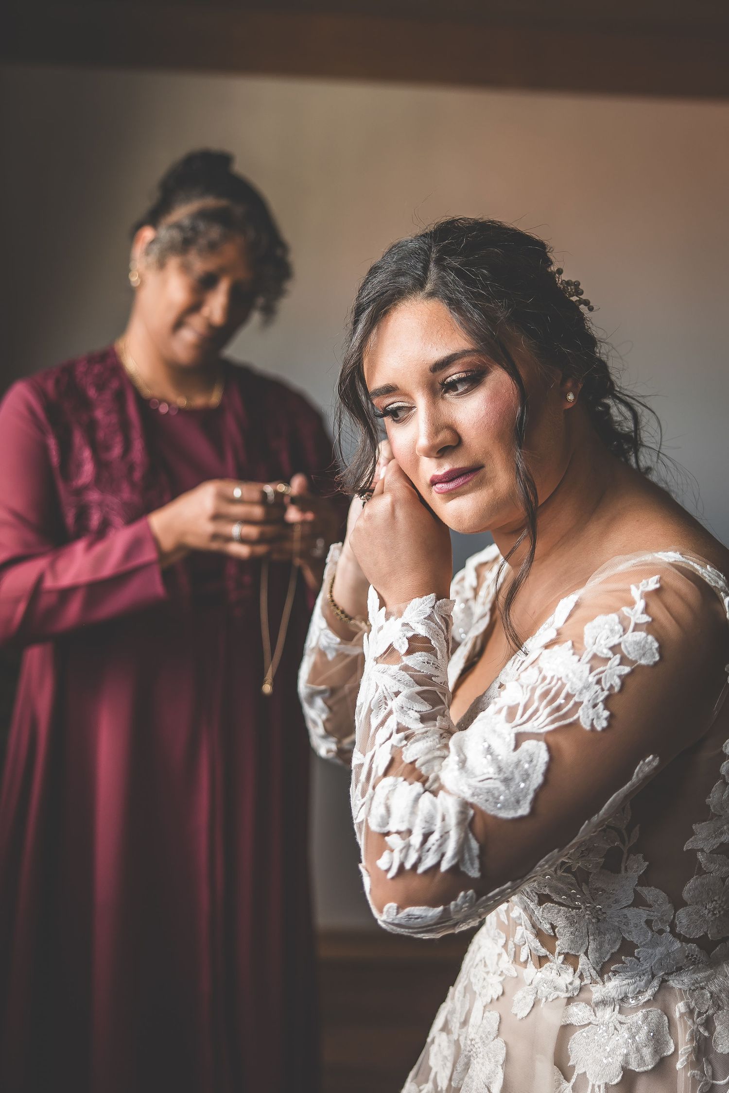 A stunning bridal portrait showcasing an elegant lace wedding dress with long sleeves in natural window light.