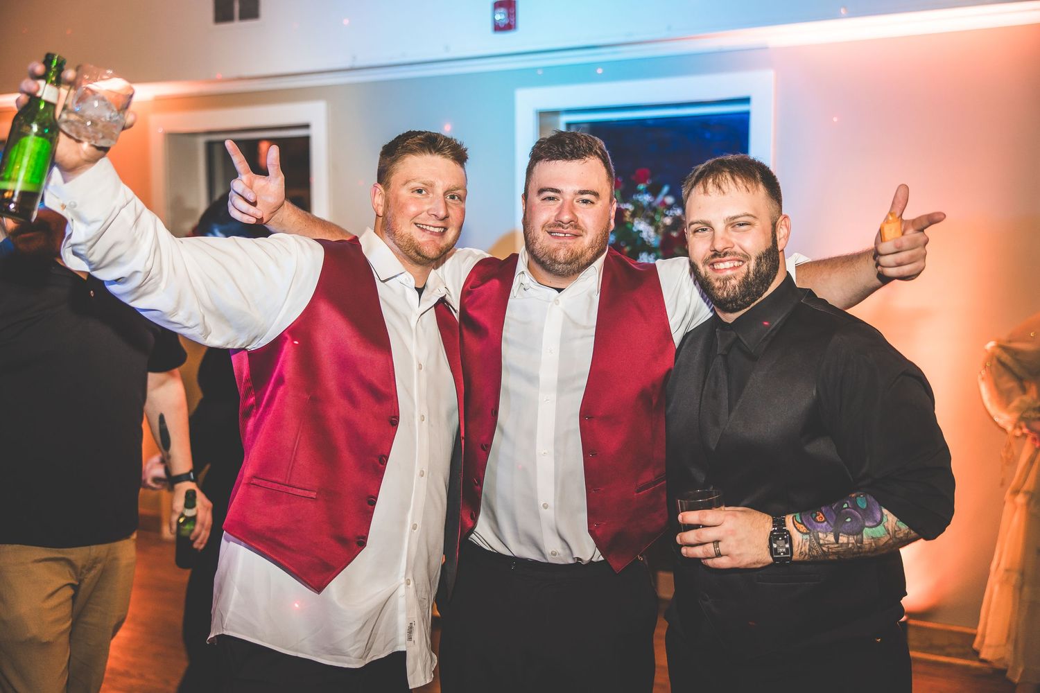 Wedding party members in burgundy and white attire dancing and celebrating at the reception.