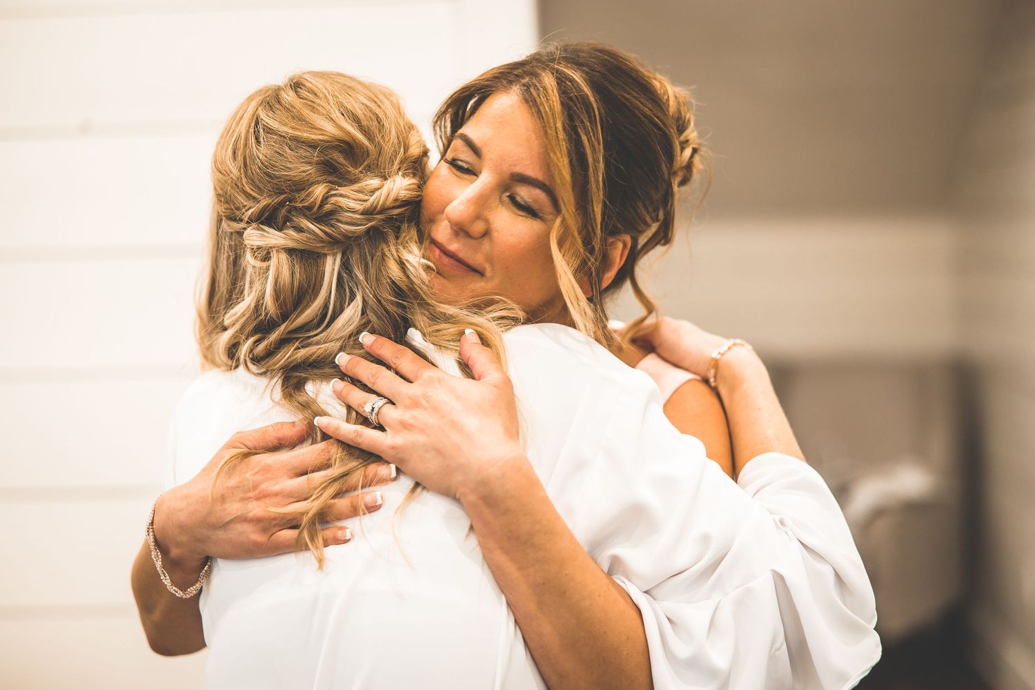 Emotional moment between two women embracing during wedding preparations.