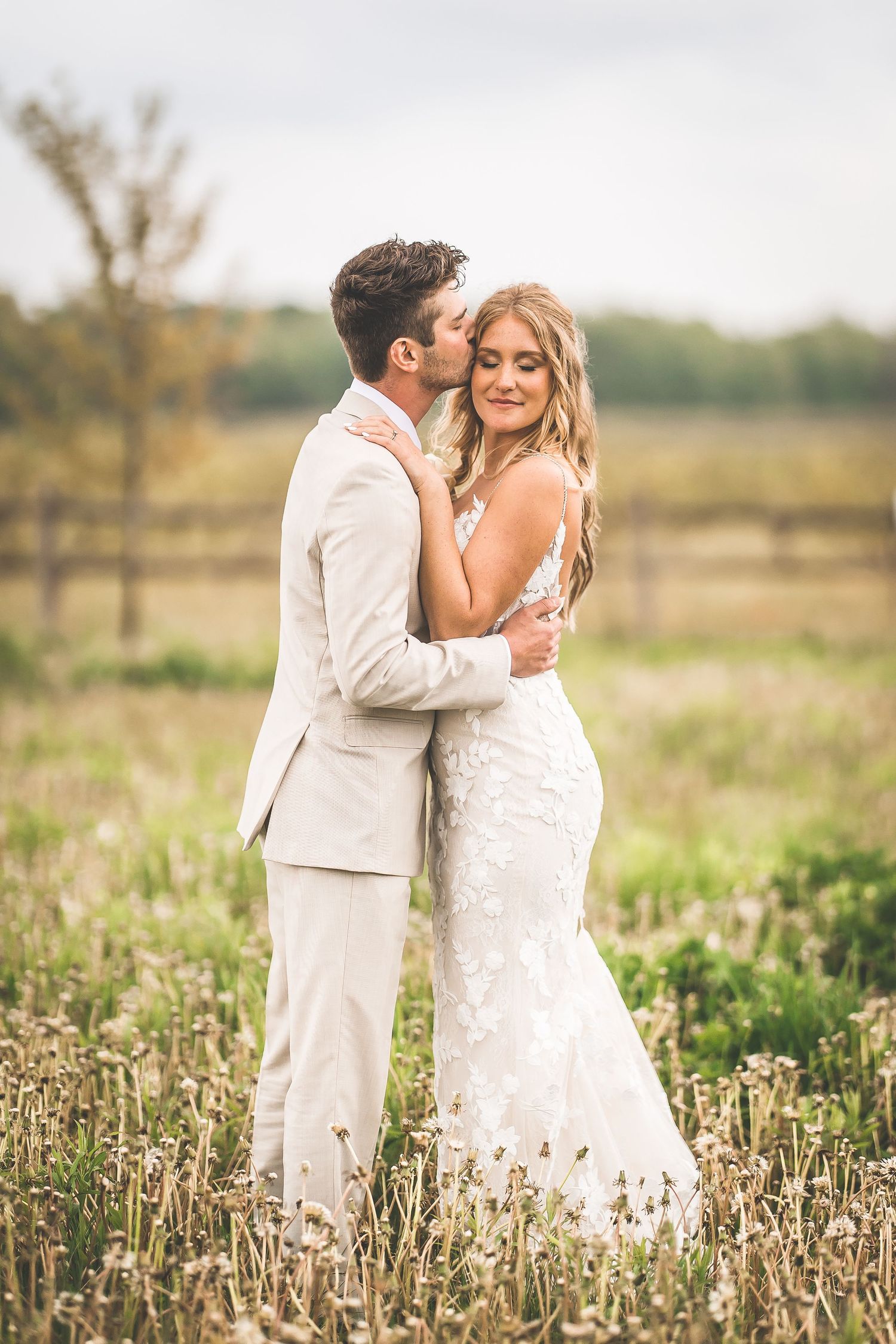 Wedding couple shares romantic moments in a field of dried flowers and tall grass.