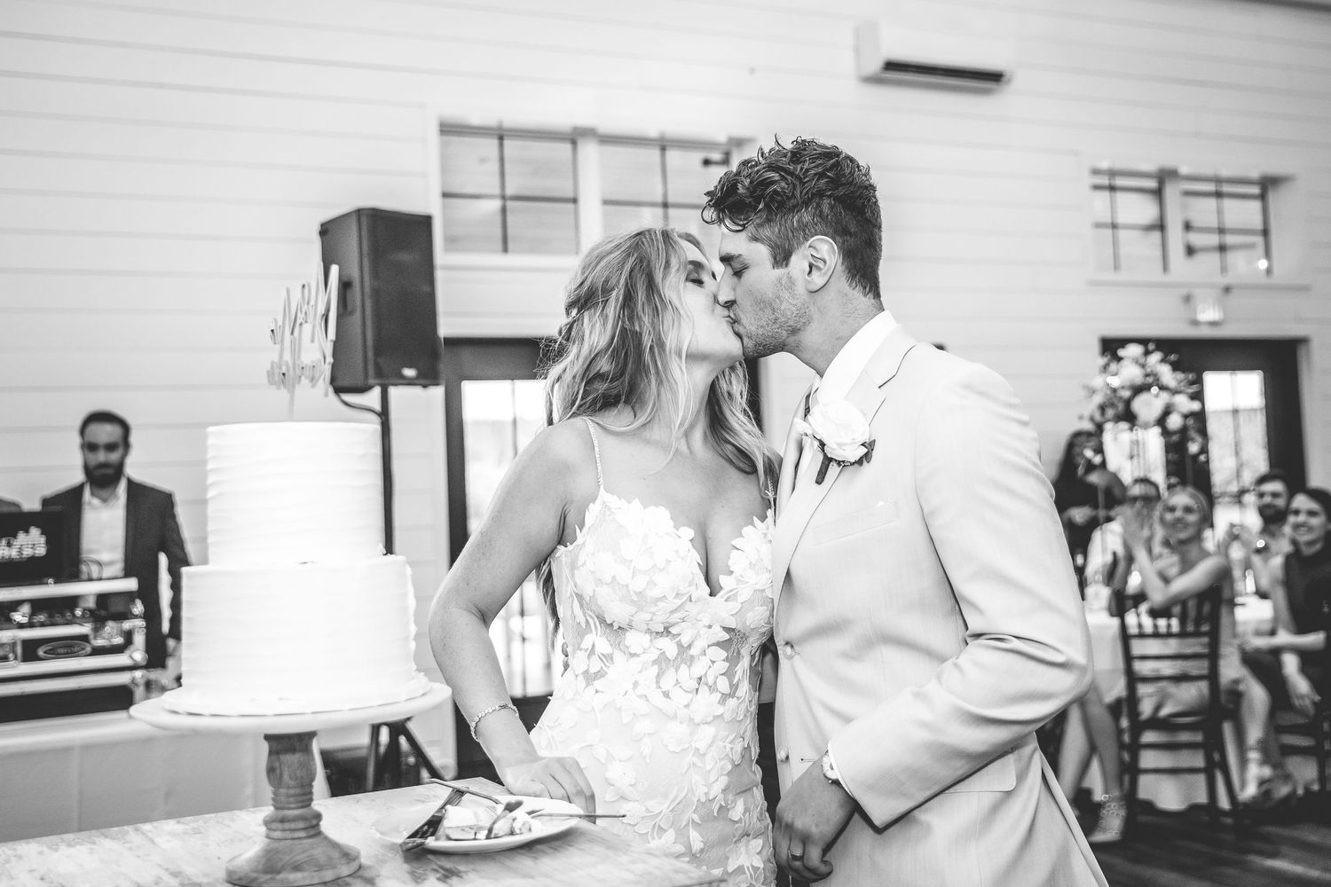 Black and white photo of couple sharing romantic moment during wedding cake cutting.