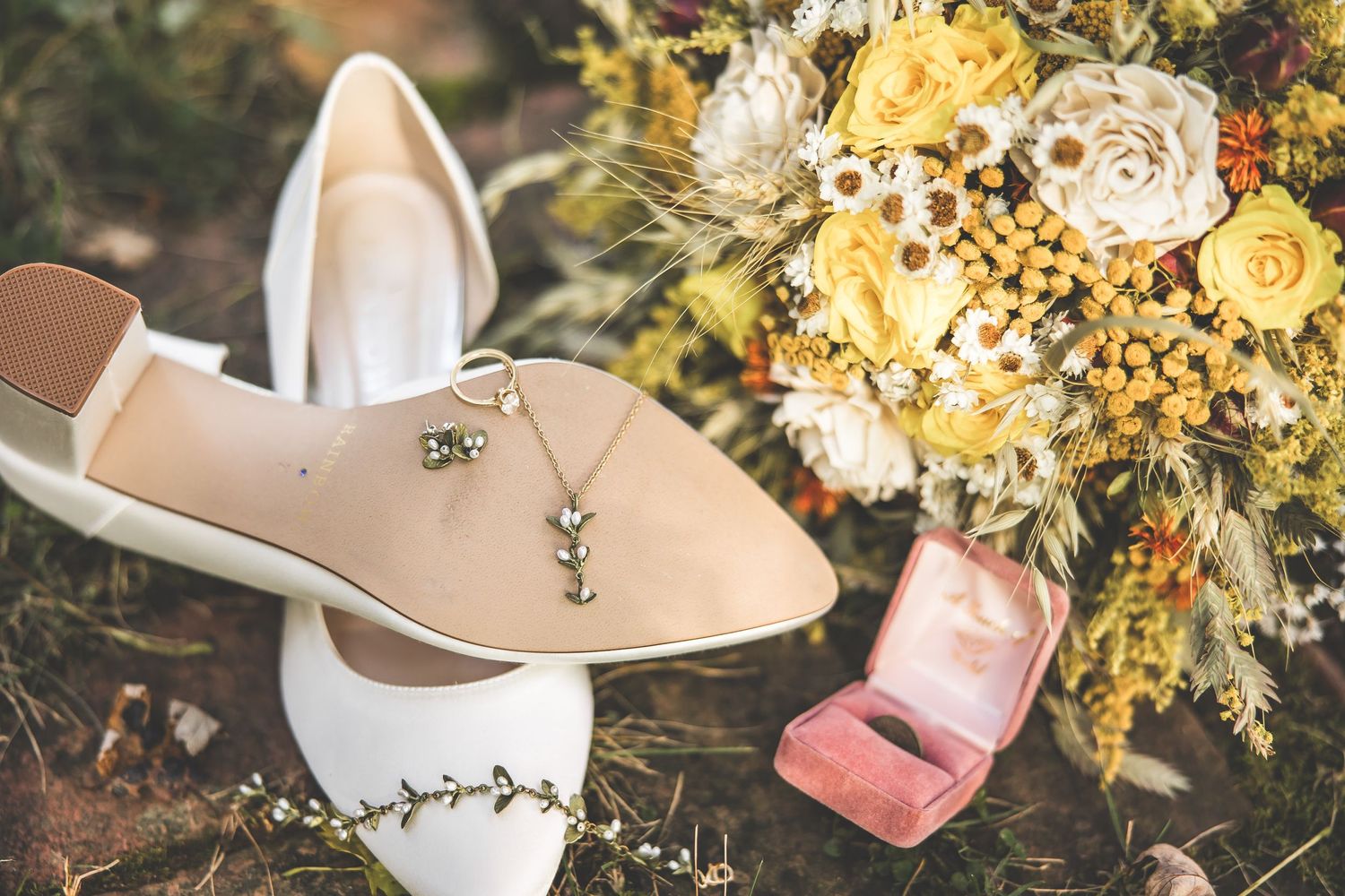 Wedding detail shot of bridal shoes and yellow floral arrangements.