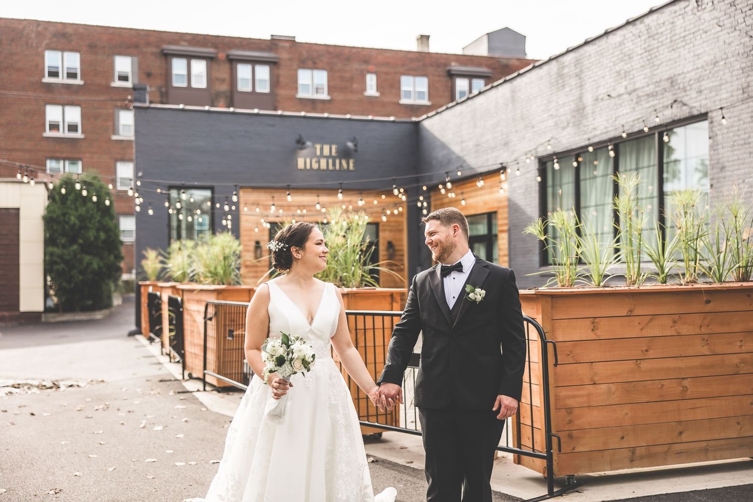 Couple walks outside modern urban venue with wooden patio features and brick walls.