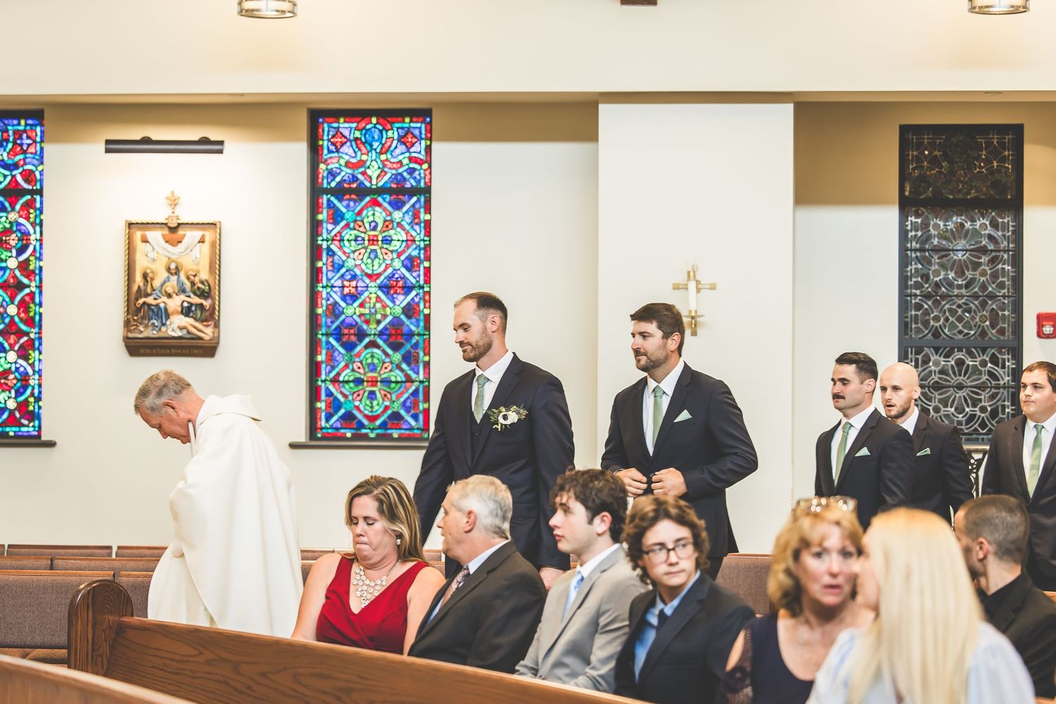 Panoramic view of a church interior with stained glass windows and wedding guests seated in pews.