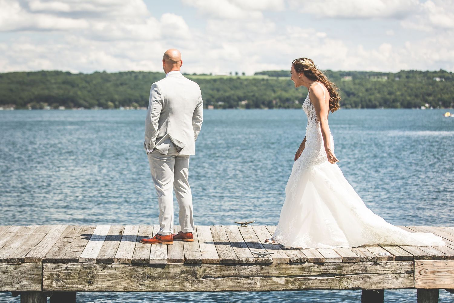 Couple stands on stone pier overlooking scenic lake on their wedding day.