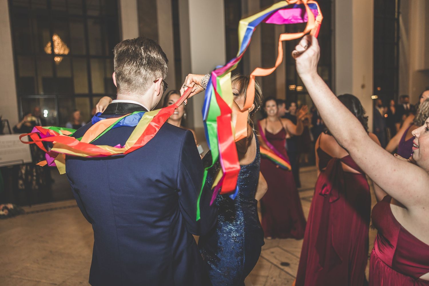 Guests wave colorful ribbon streamers during festive wedding reception dance.