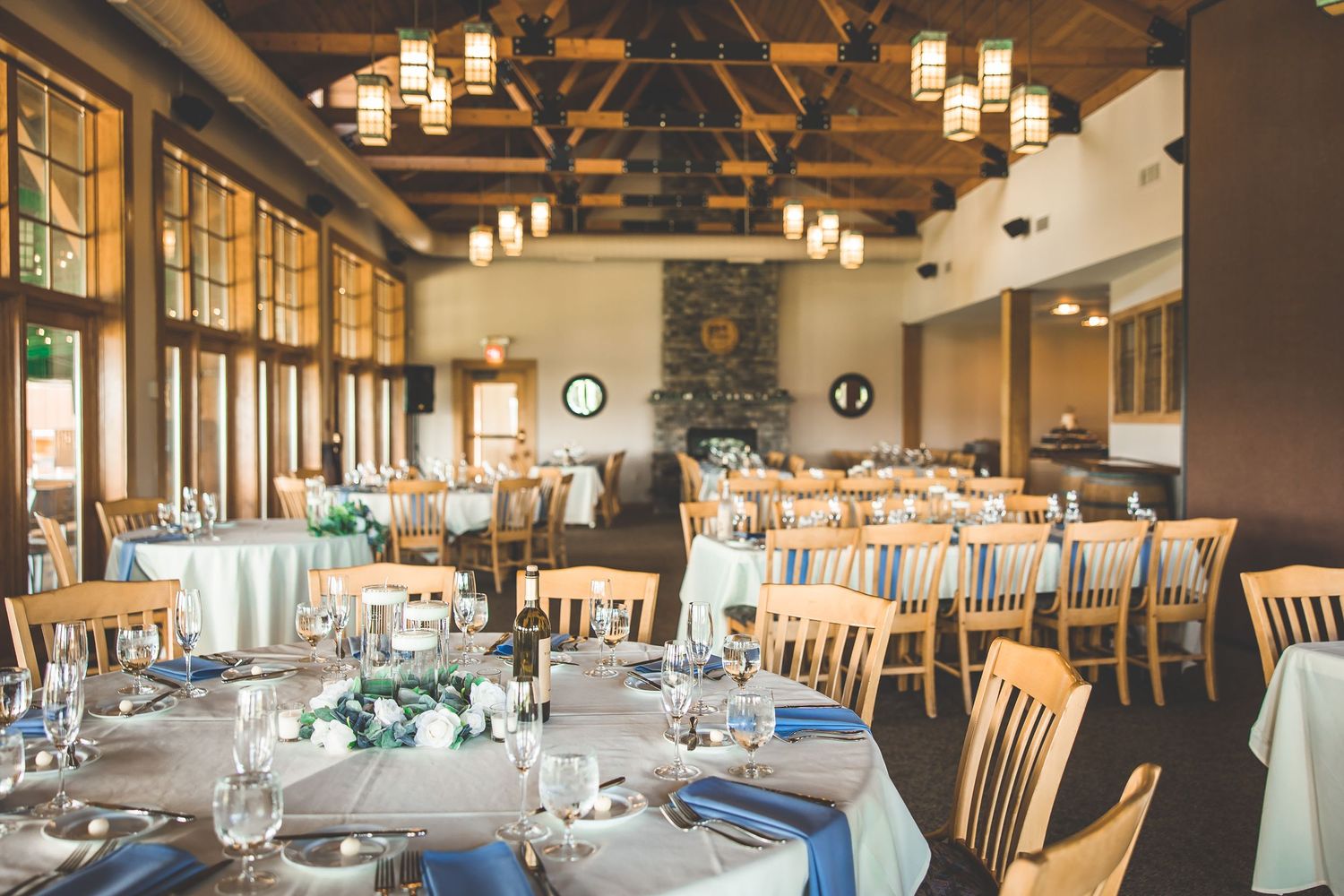 Elegant reception venue with wooden beams and pendant lighting over dining tables.