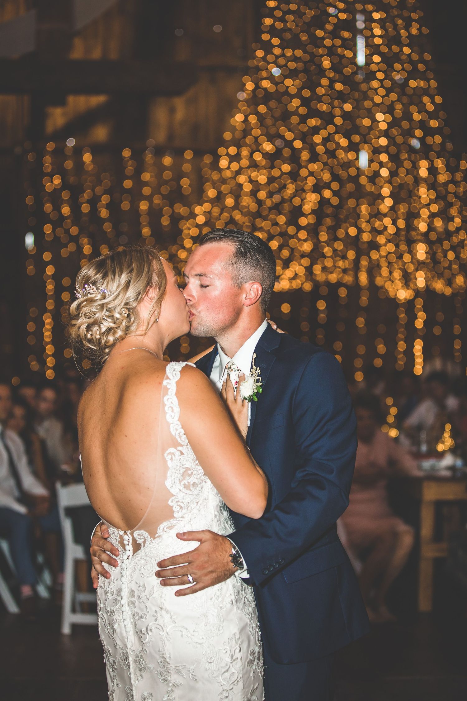 Newlyweds share a tender moment during their first dance under glowing amber lights.
