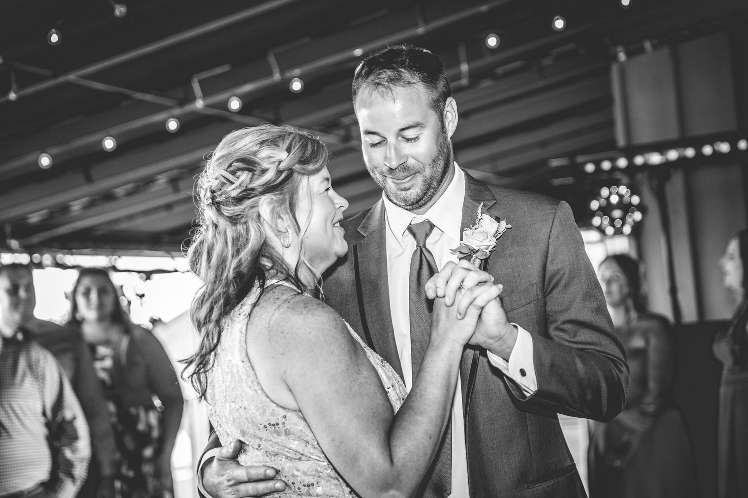 Couples dancing together at an indoor wedding reception with string lights and festive atmosphere.