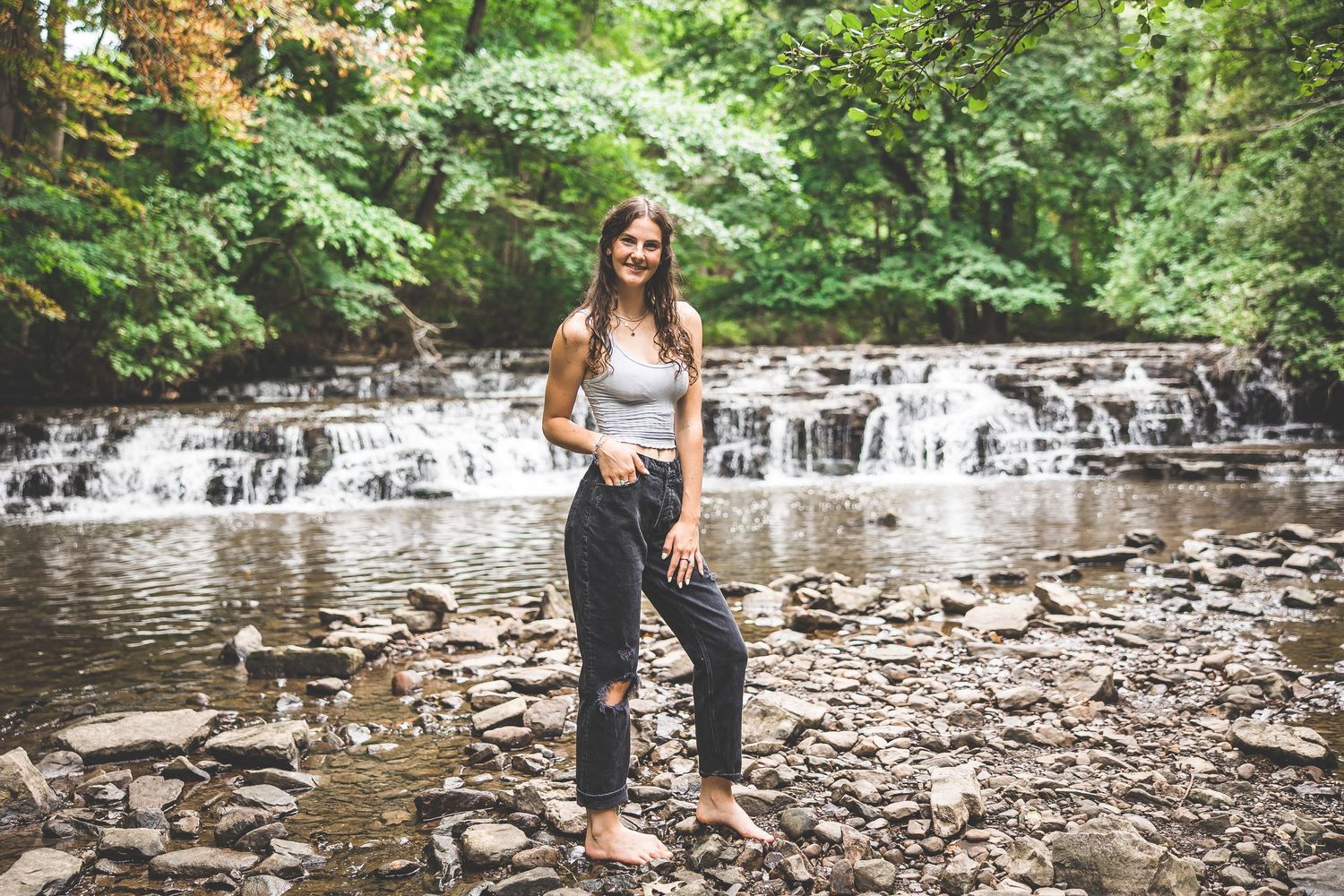 Couple exploring a scenic rocky creek surrounded by lush summer greenery.