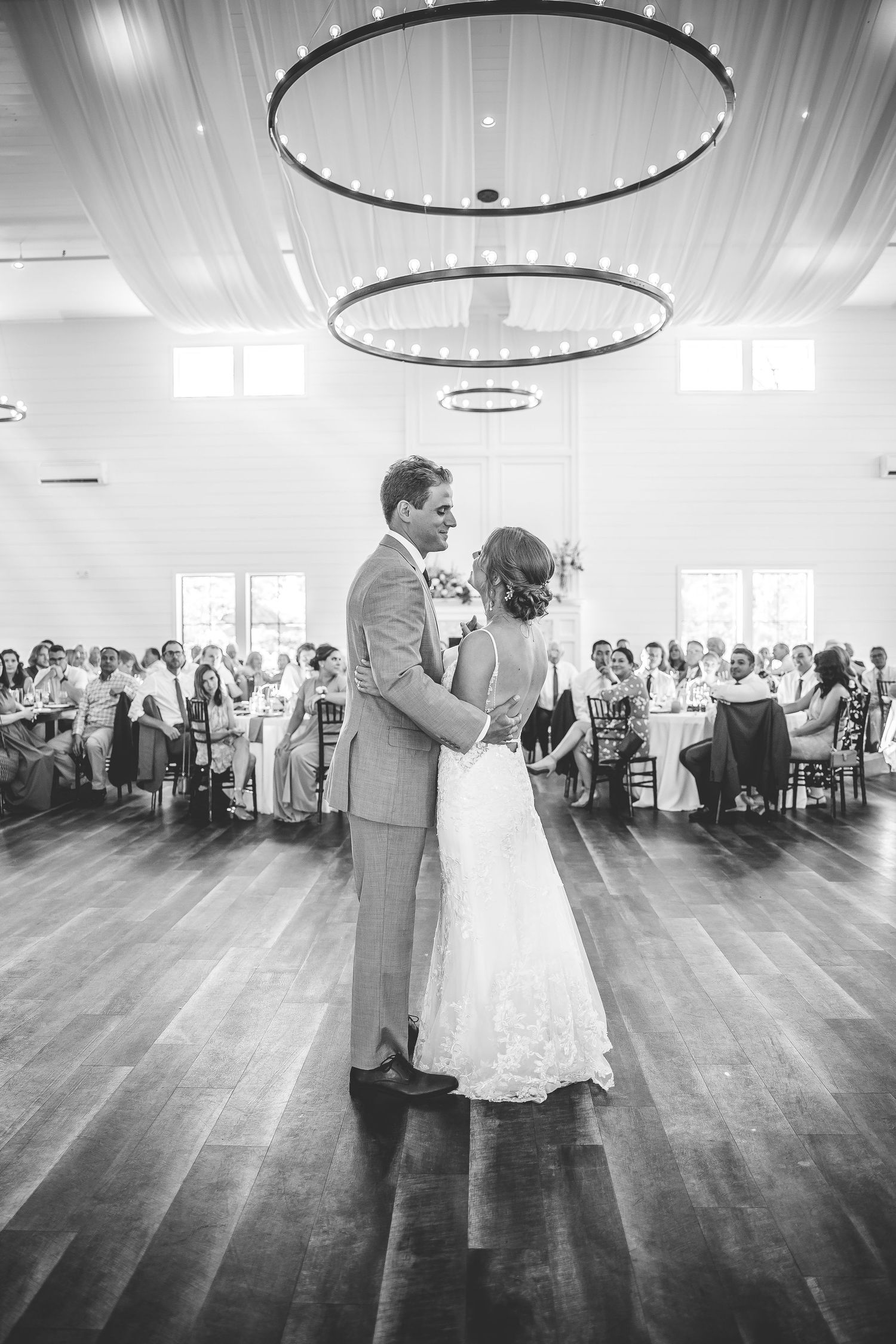 Black and white photo of a wedding couple's first dance surrounded by guests.