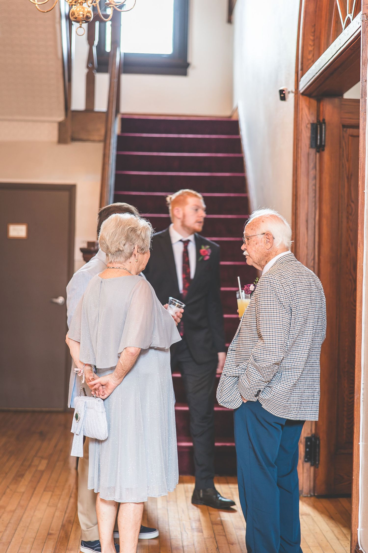 Elderly couple sharing a tender moment together in a hallway with wooden floors and walls.