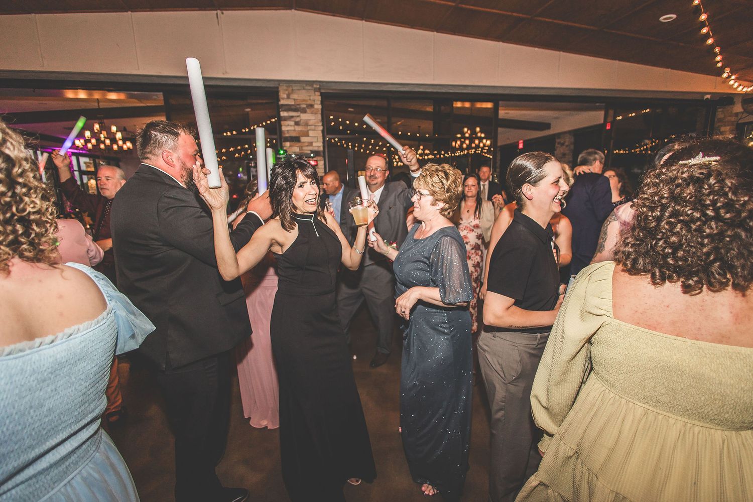 Panoramic view of wedding reception dance floor with guests celebrating under ambient lighting.