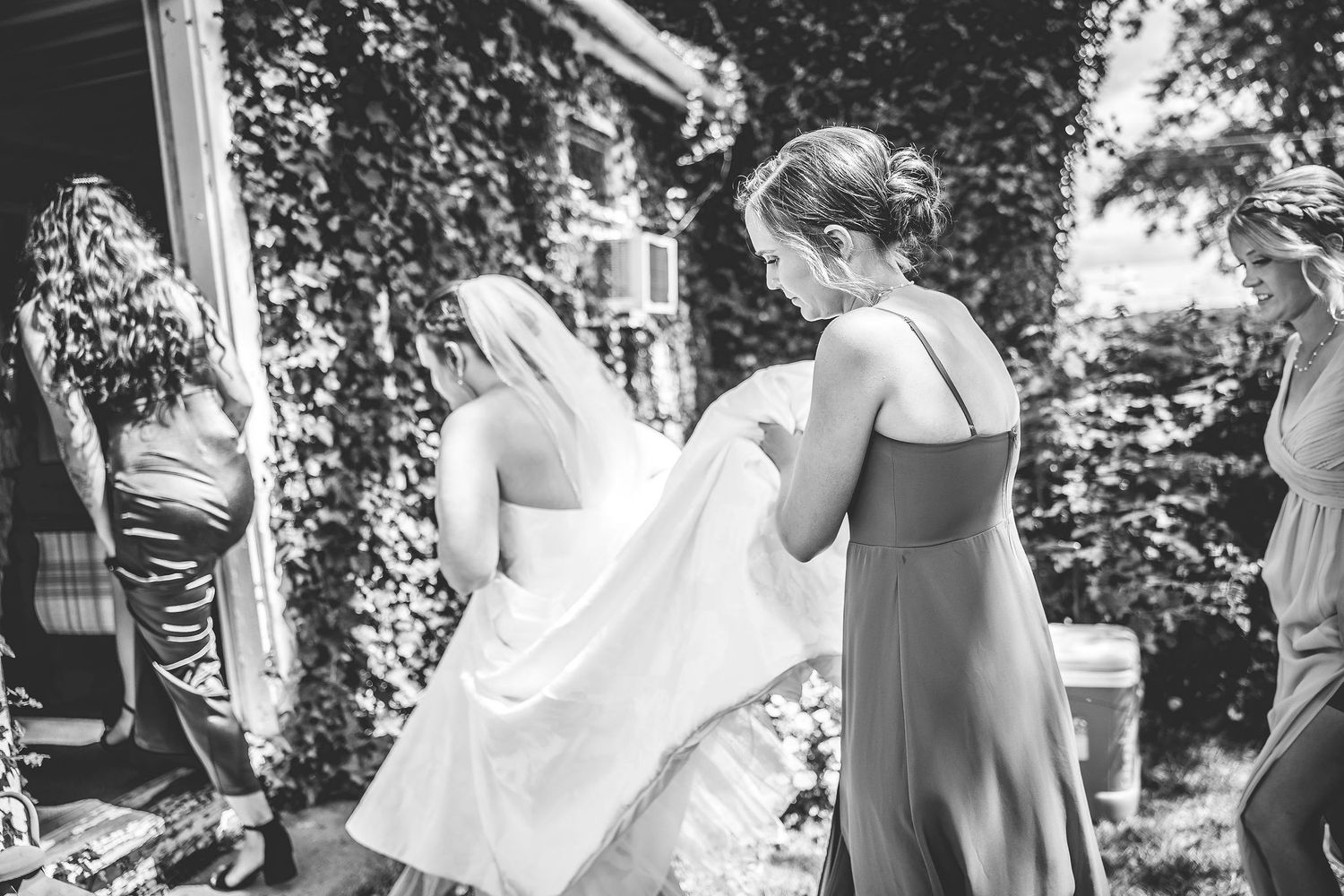 Black and white photo capturing reactions during a wedding dress reveal moment.