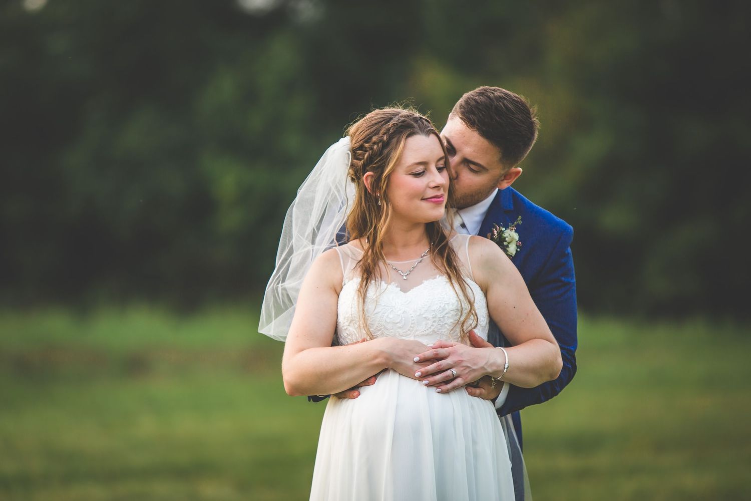 Romantic wedding portraits captured in a lush green field.