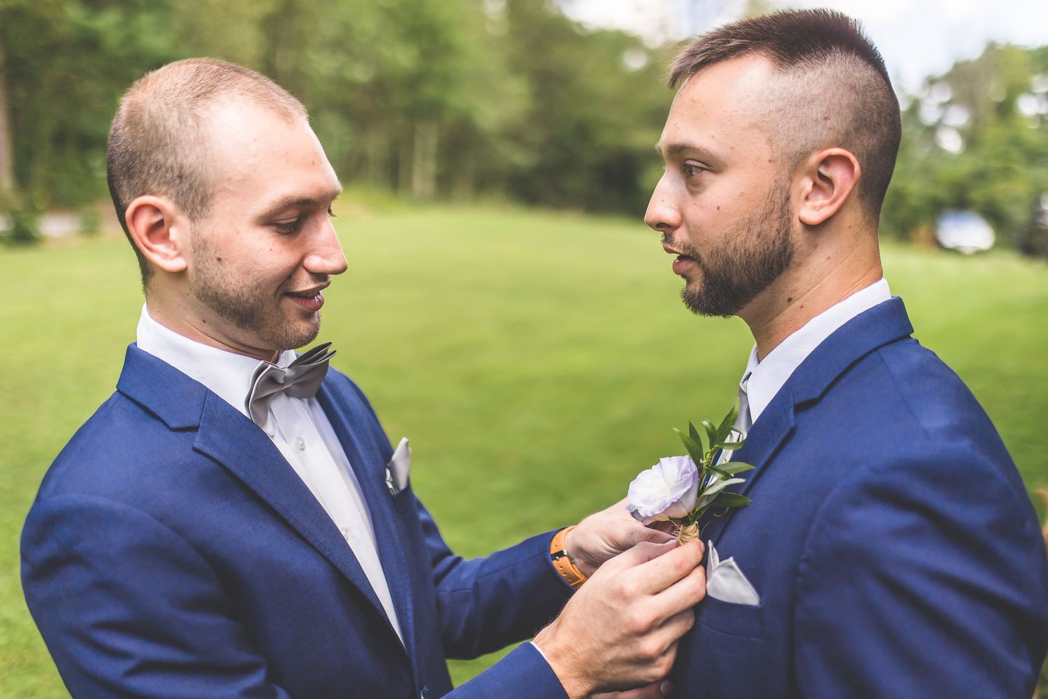 Groomsmen in navy suits adjust their ties before the ceremony.