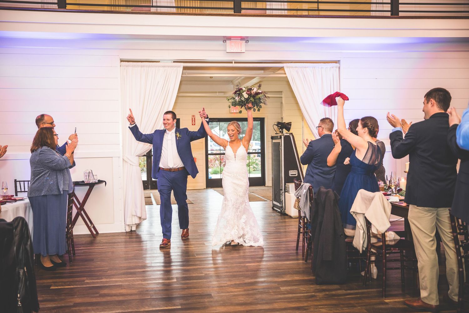 Wedding reception dance floor panorama showing guests celebrating in an elegant white venue.