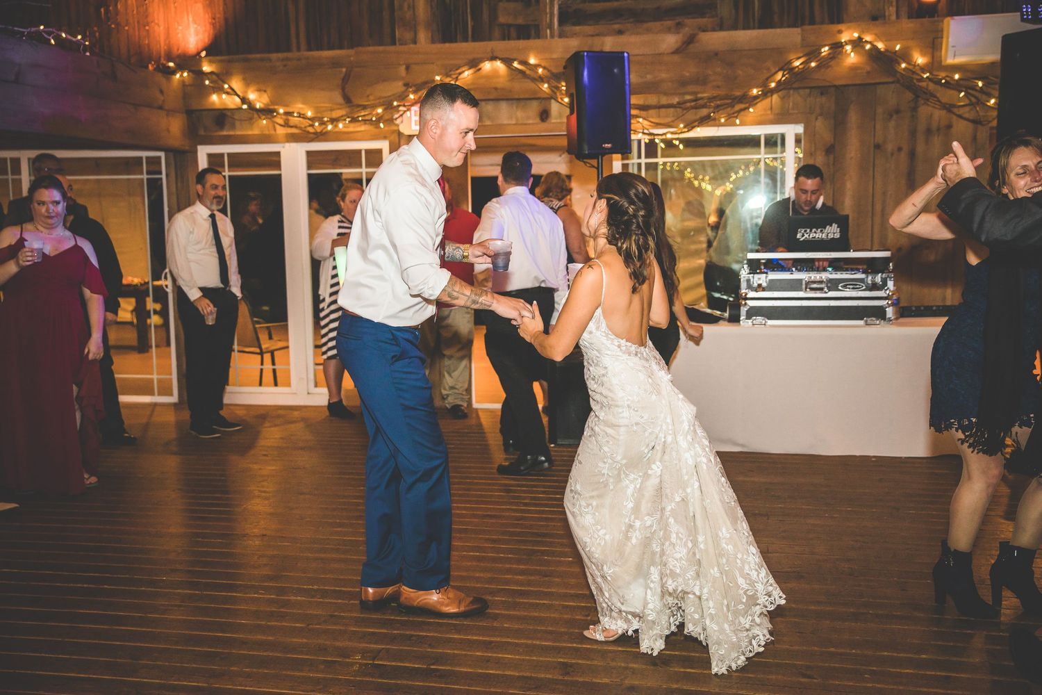 Wedding reception dance floor with string lights and rustic barn setting.