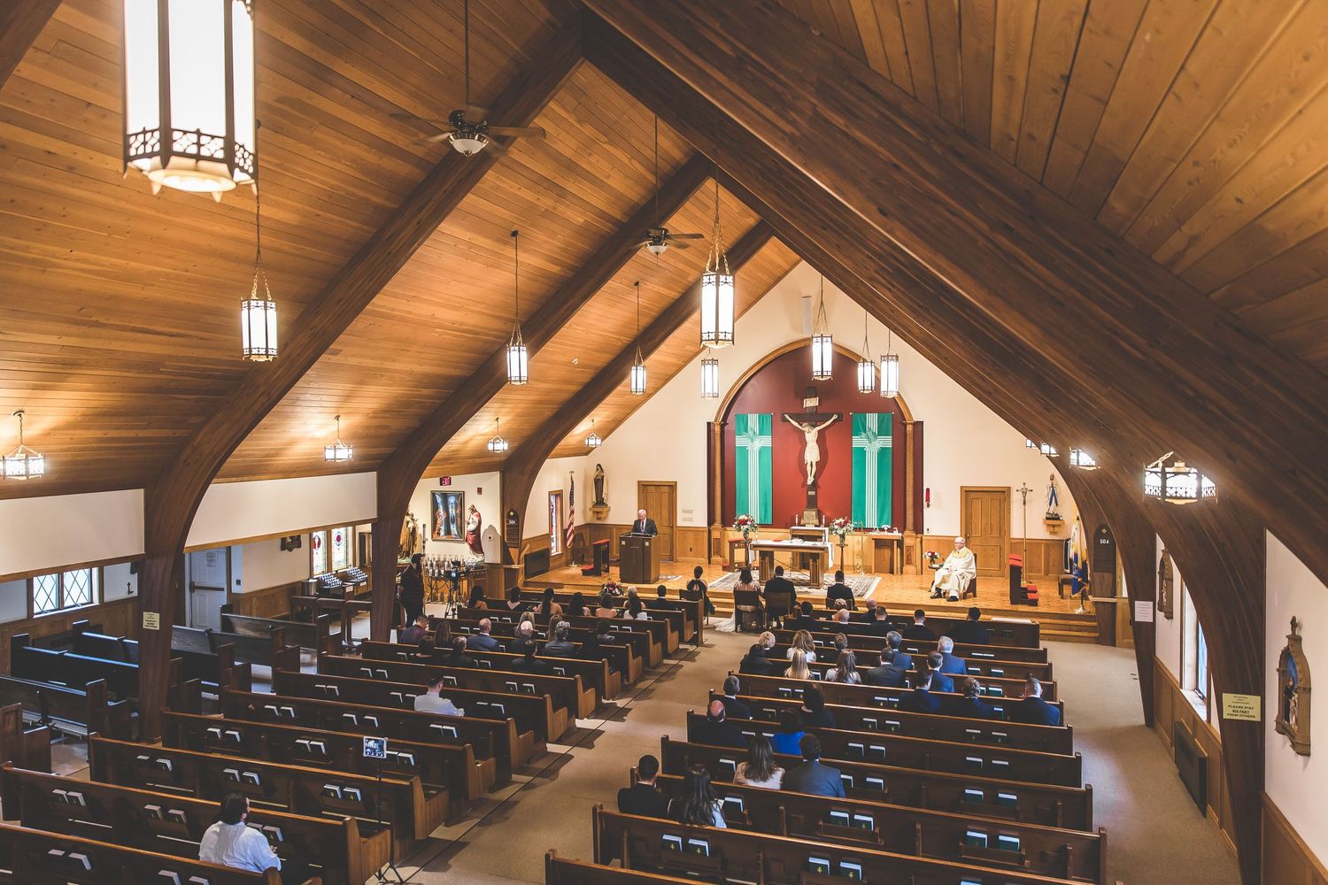 Wide angle view of empty church sanctuary with wooden beams and pews.