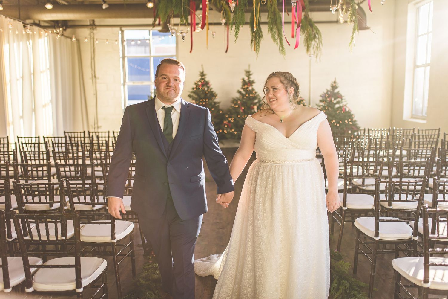 Wedding ceremony venue with wooden chairs and evergreen trees decorated for winter.