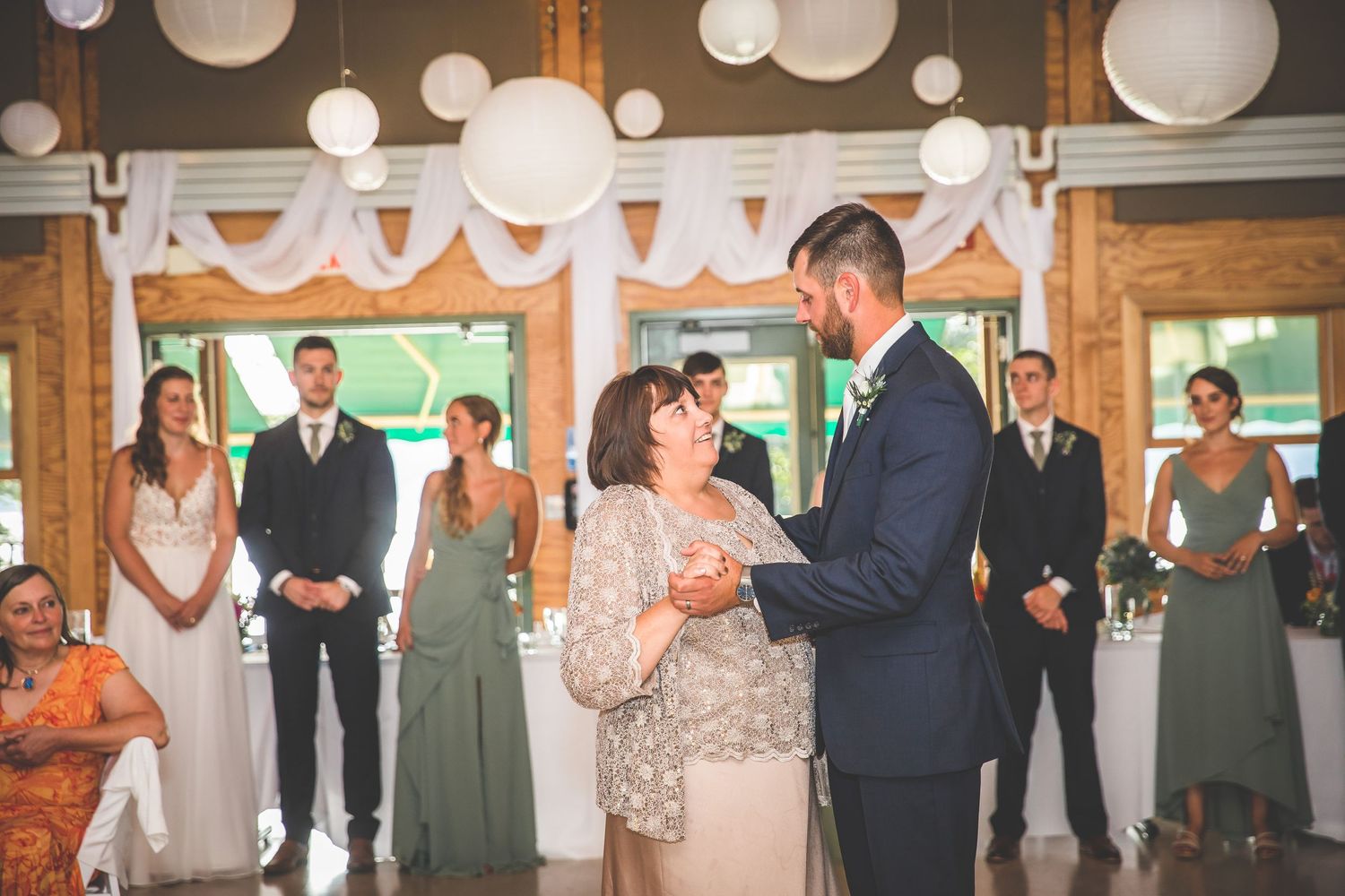 Rustic wedding venue interior with hanging paper lanterns and exposed wooden beams.