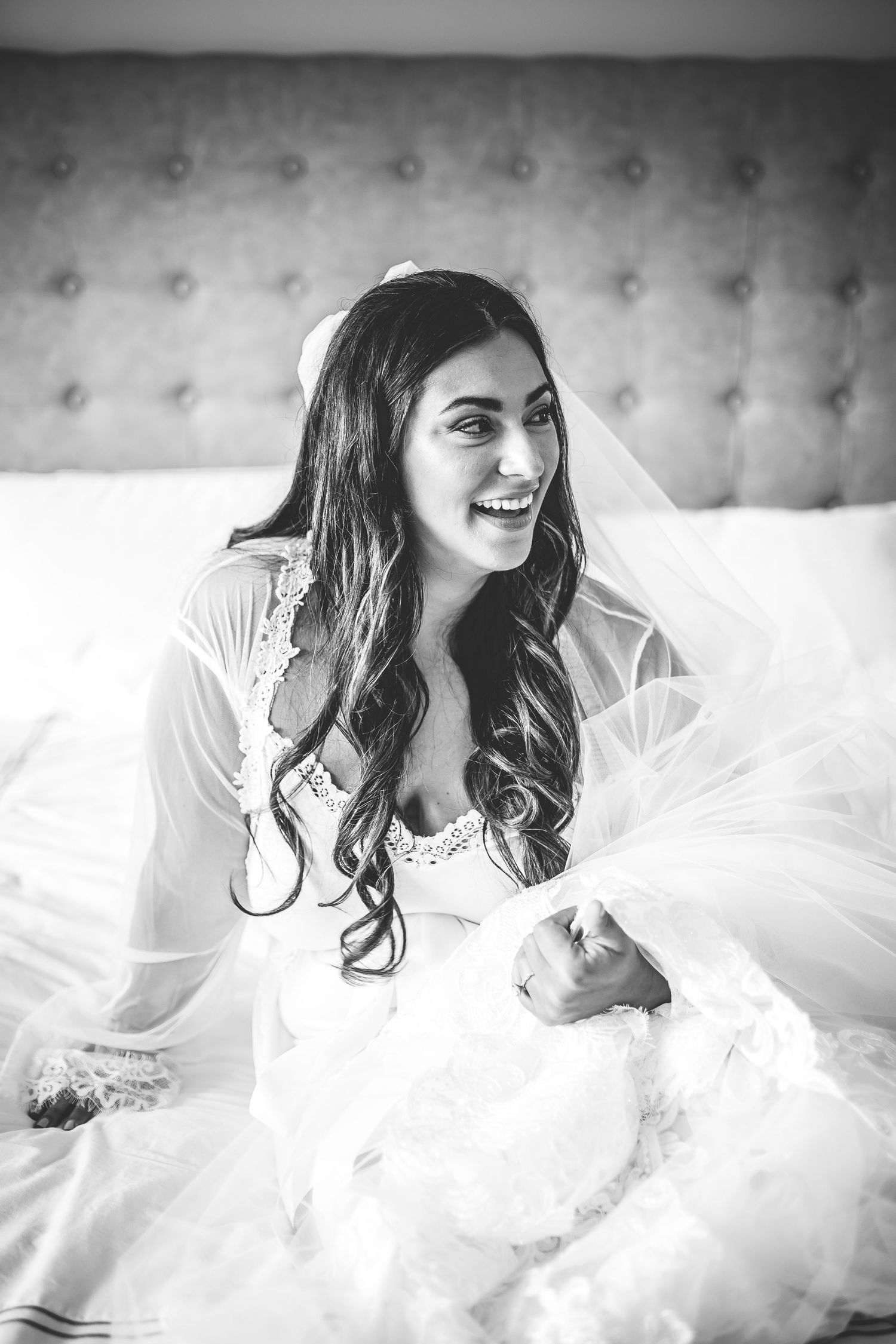 Black and white portrait series of bride in lace wedding gown laying on tufted couch.