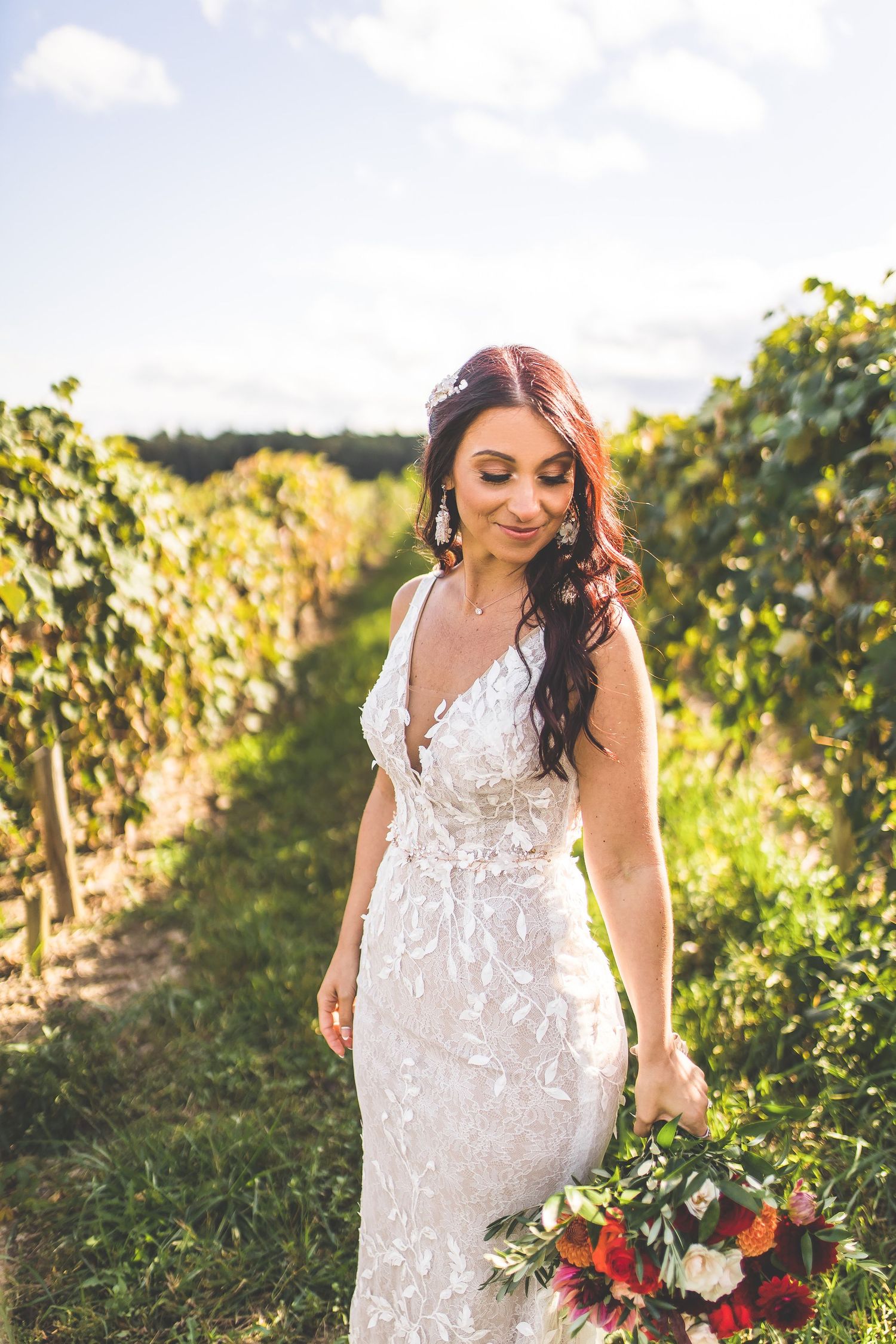 White lace wedding dress details photographed in a sunny vineyard setting.