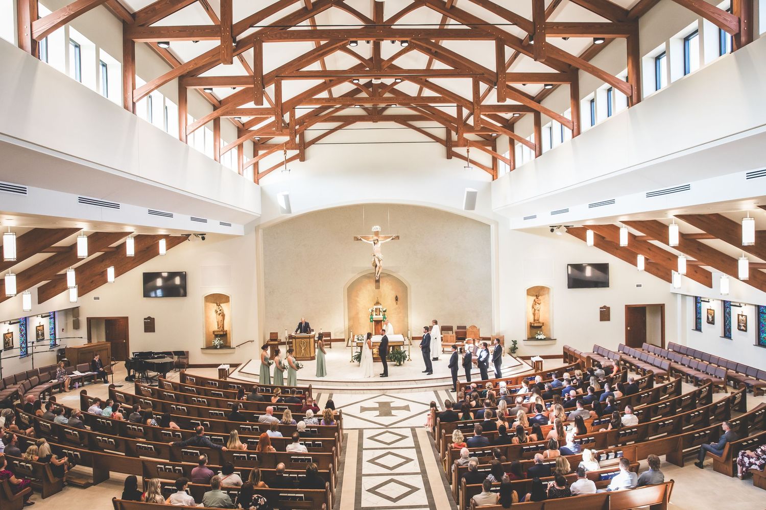 A panoramic view of a modern church interior with exposed wooden beams and filled pews.