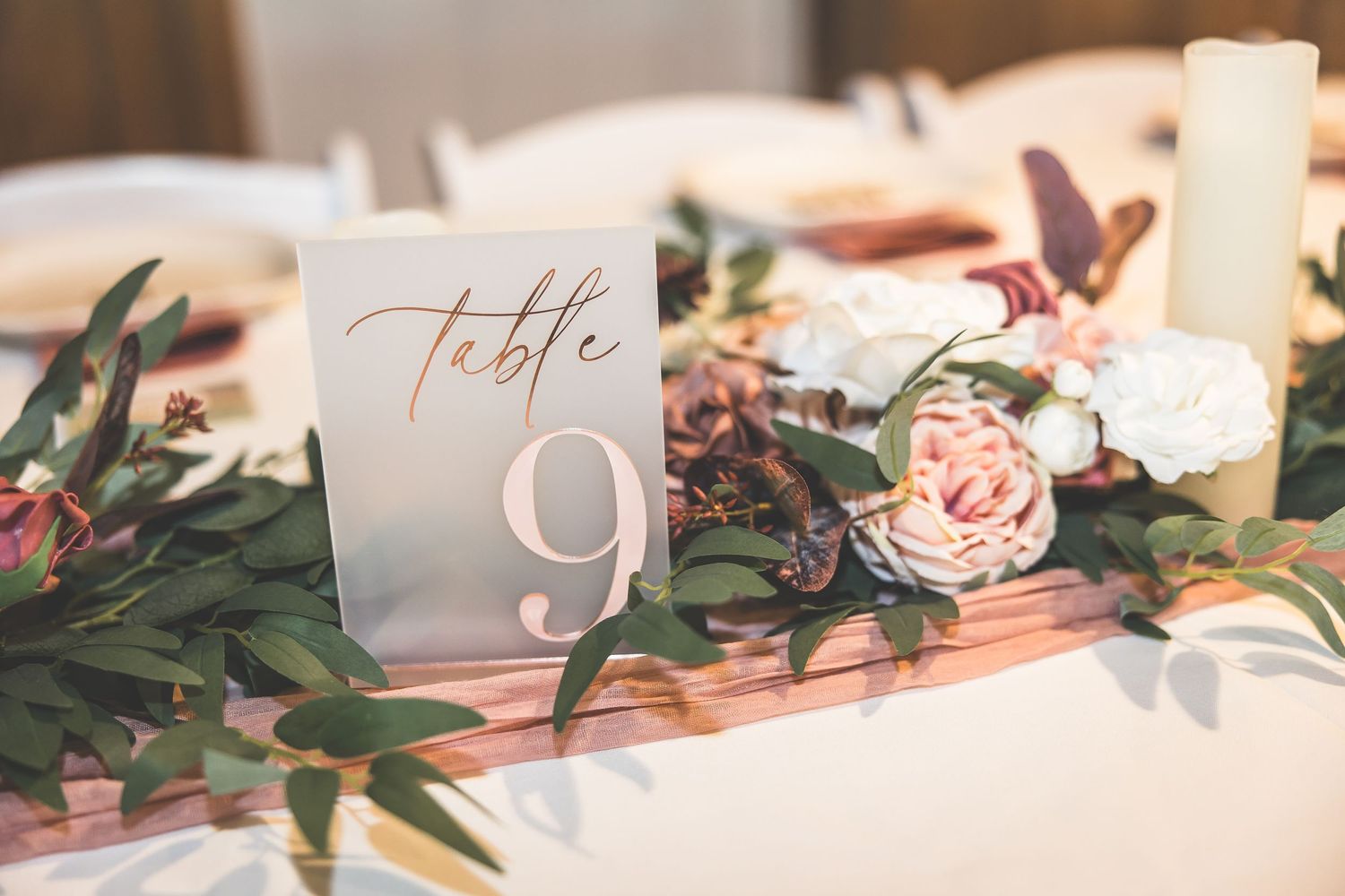 Elegant table settings with pink floral centerpieces and calligraphy table numbers.