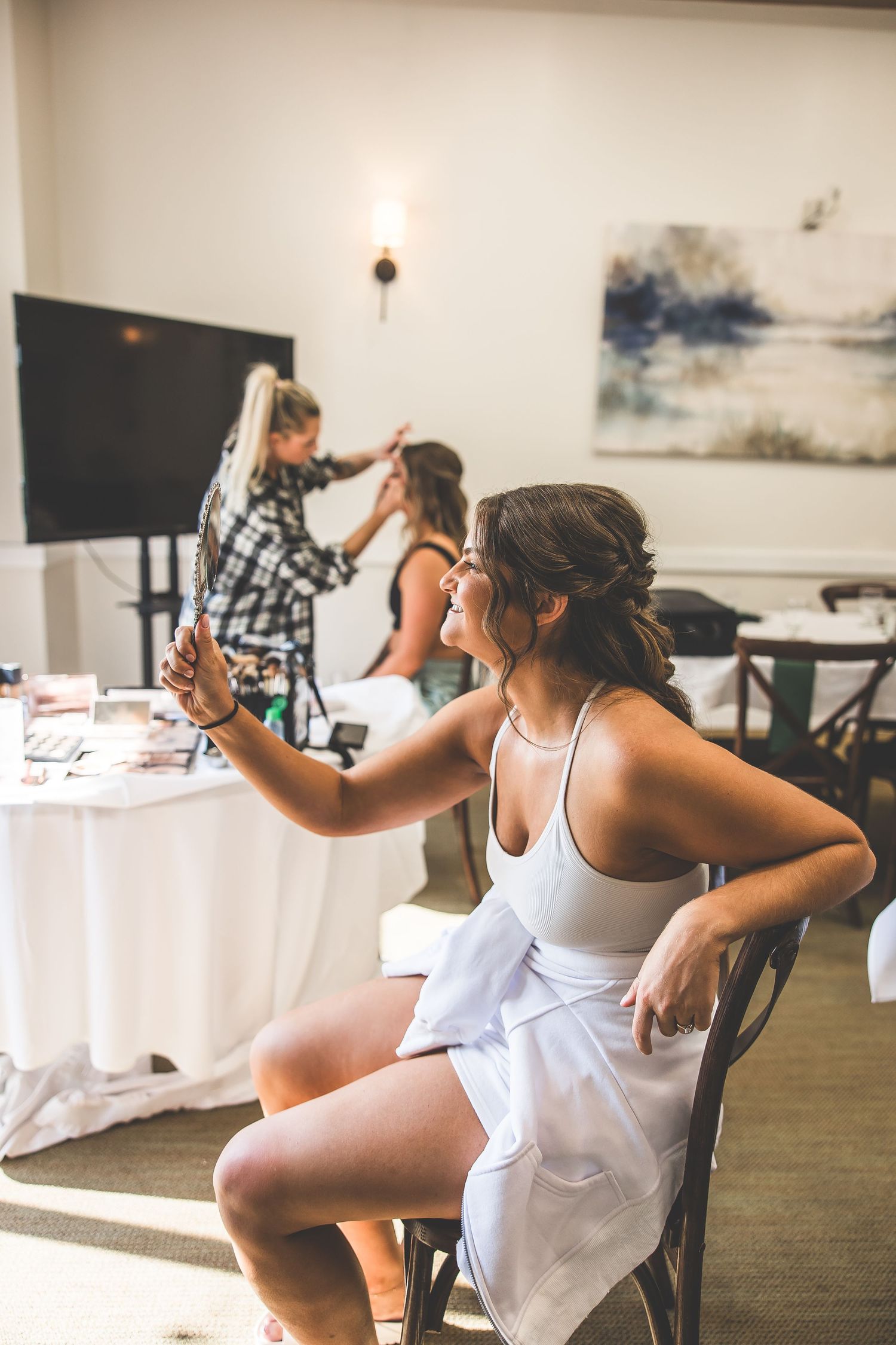 Women in white tank tops practicing dance moves in bright studio space.