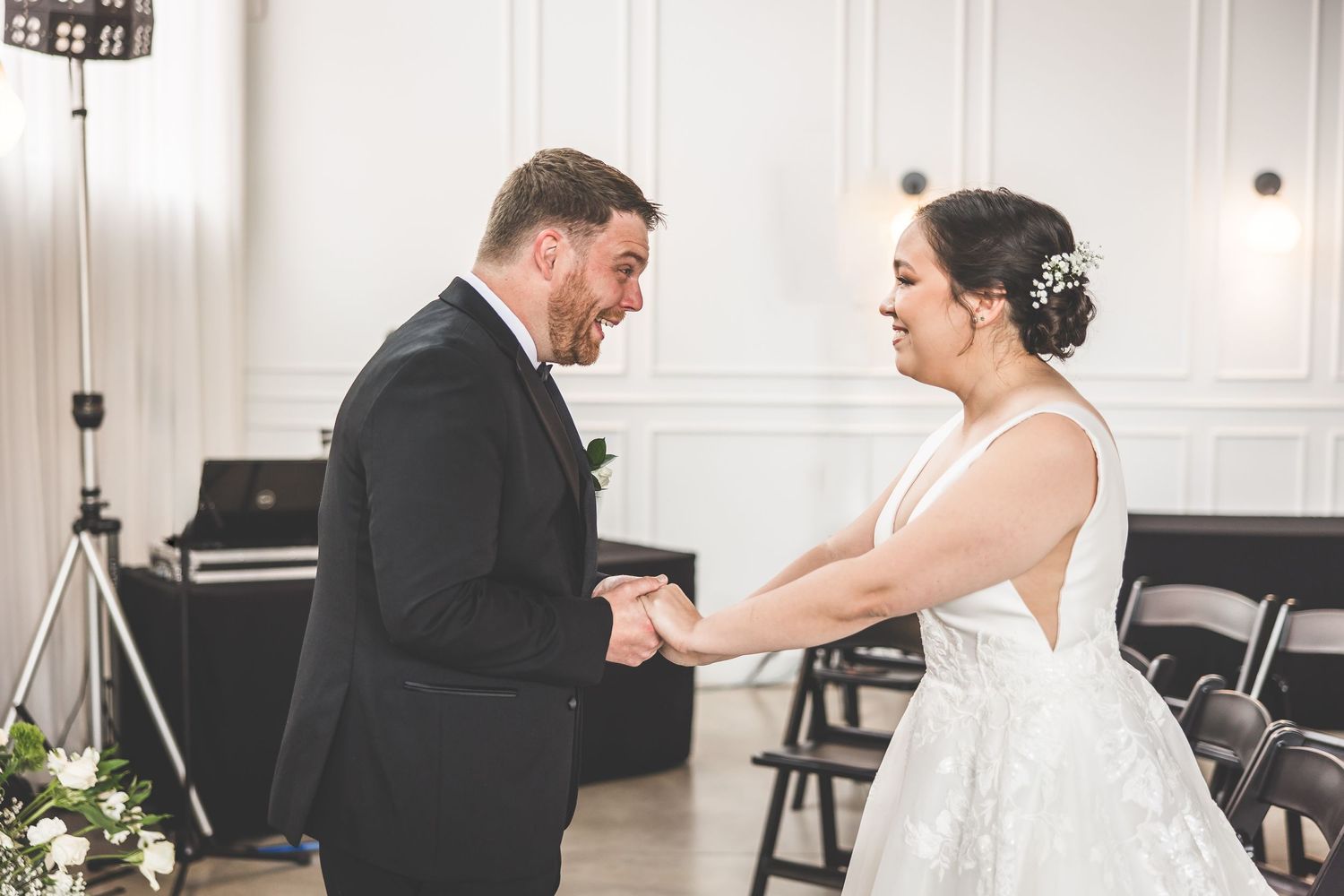 Sweet candid reactions during a wedding first look in an elegant white-walled venue.