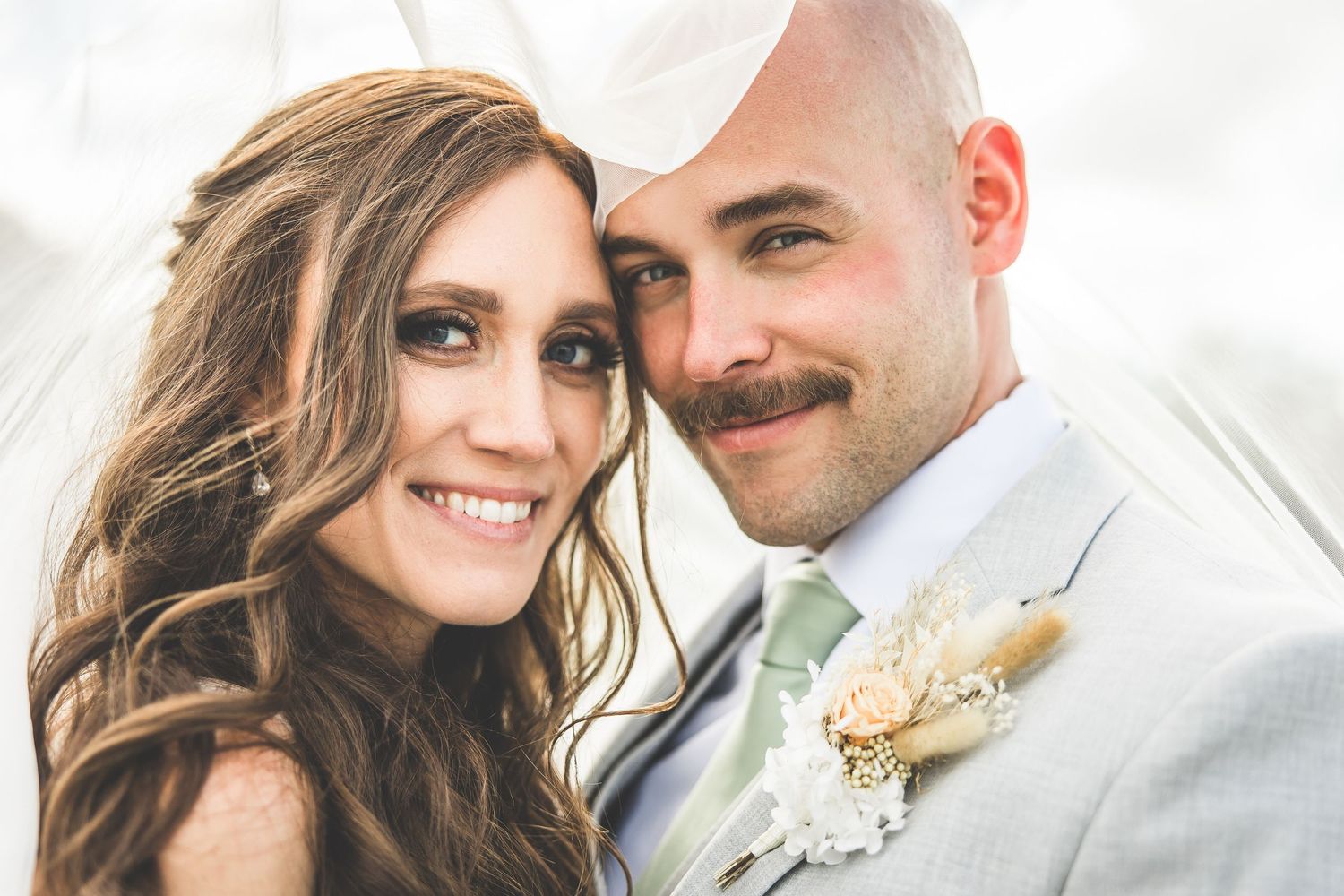 Close-up wedding portraits captured against a bright summer sky.
