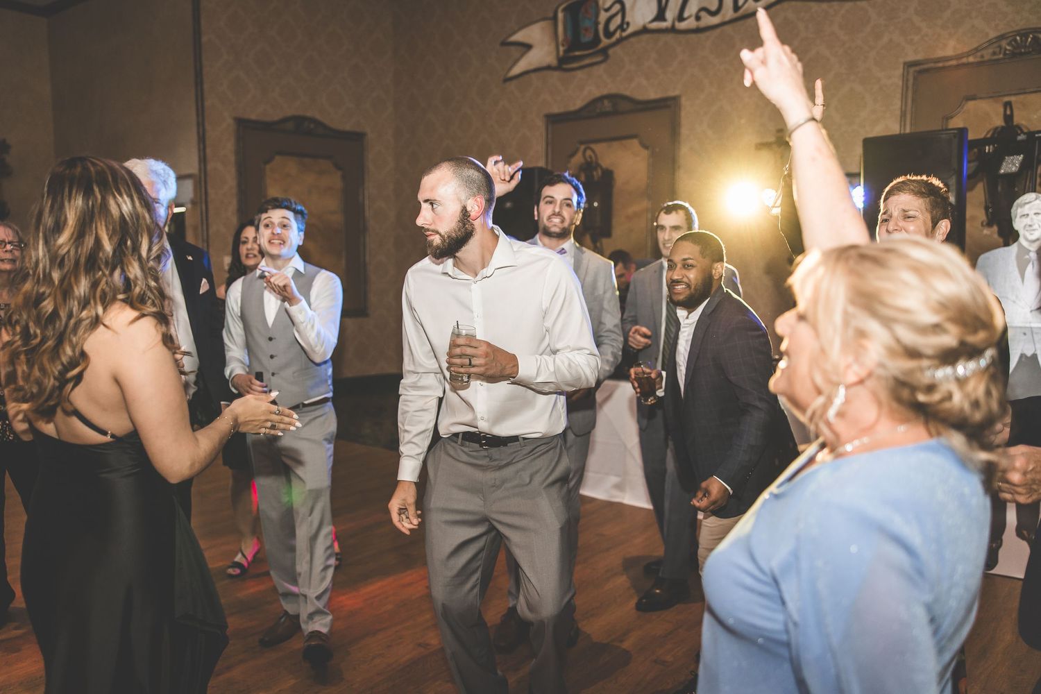 People dancing and celebrating at a wedding reception with a ballroom setting.