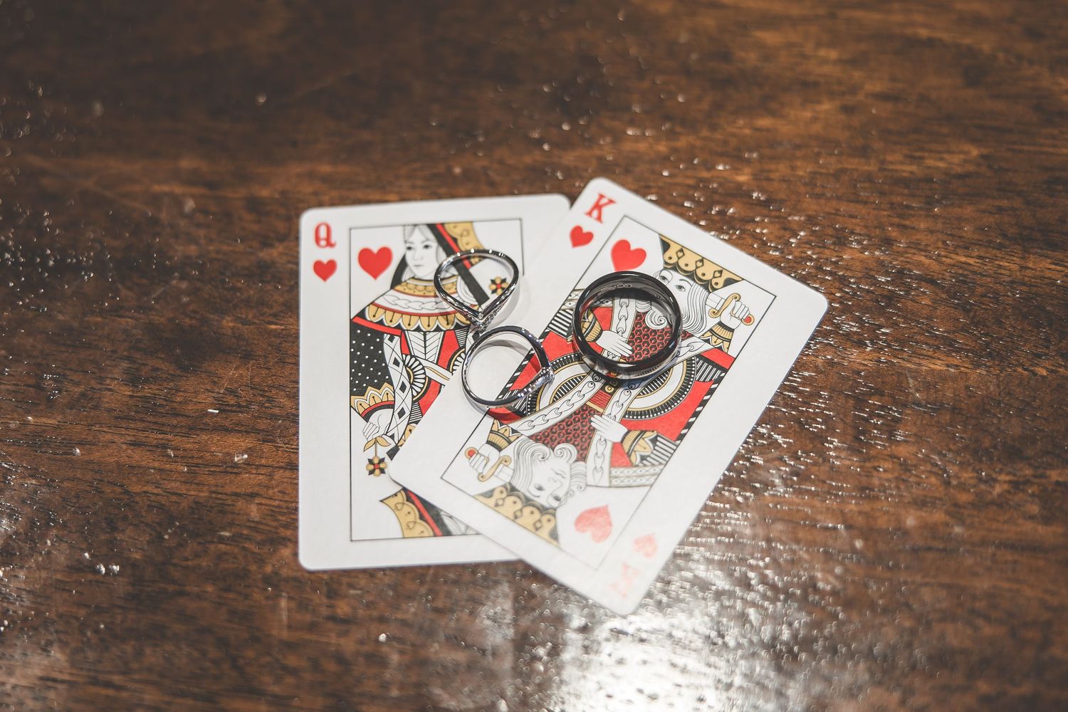 Playing cards featuring hearts and diamonds laid out on a rustic wooden table.