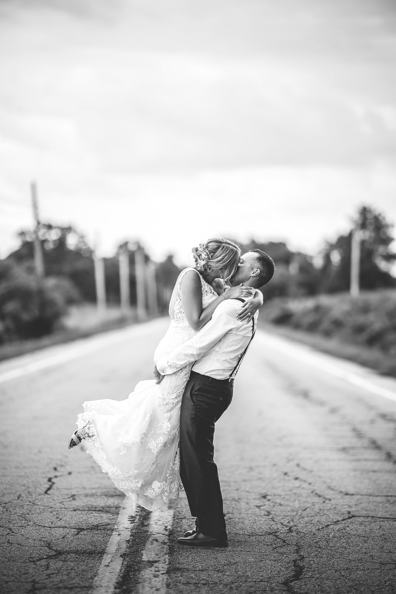Dramatic black and white wedding dance poses on an empty rural road.