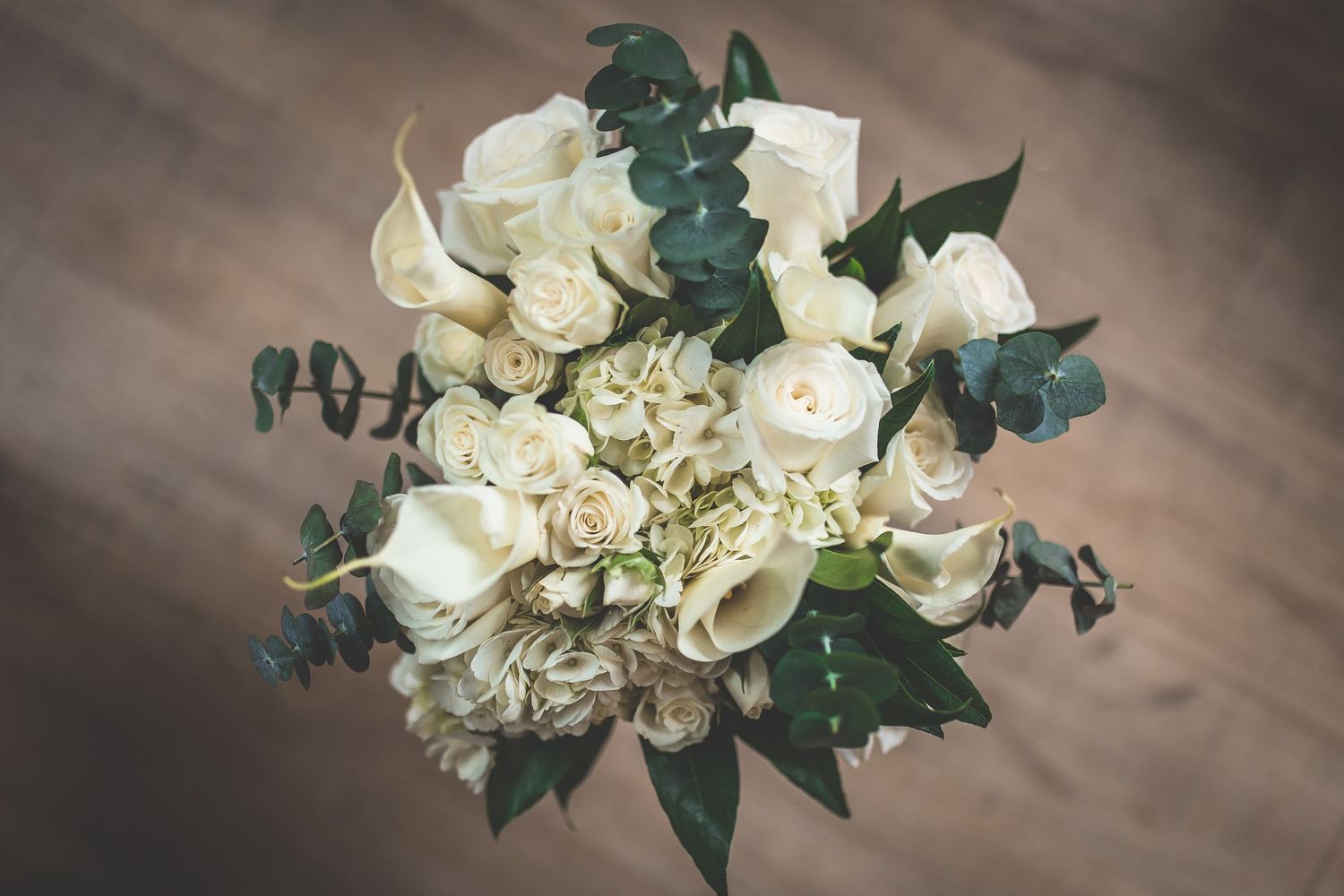 White floral bouquet with green foliage against textured background.