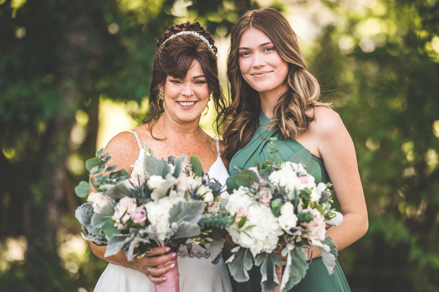 Wedding party members smile while holding elegant white and green bouquets.